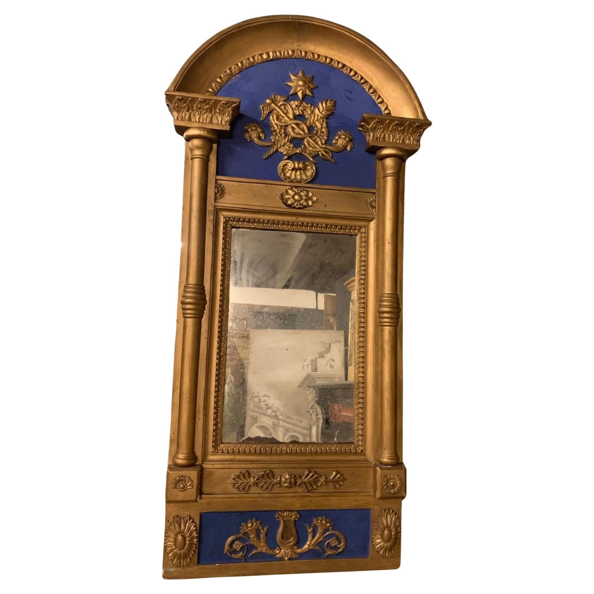 Antique Mirror da parete o console, in legno laccato blu e oro, intagliato con simboli medici, con colonne laterali, simbolo di Esculapio e Caduceo.
Esculapio è il simbolo della medicina e del sollievo ed è un segno di pace rappresentato da un
