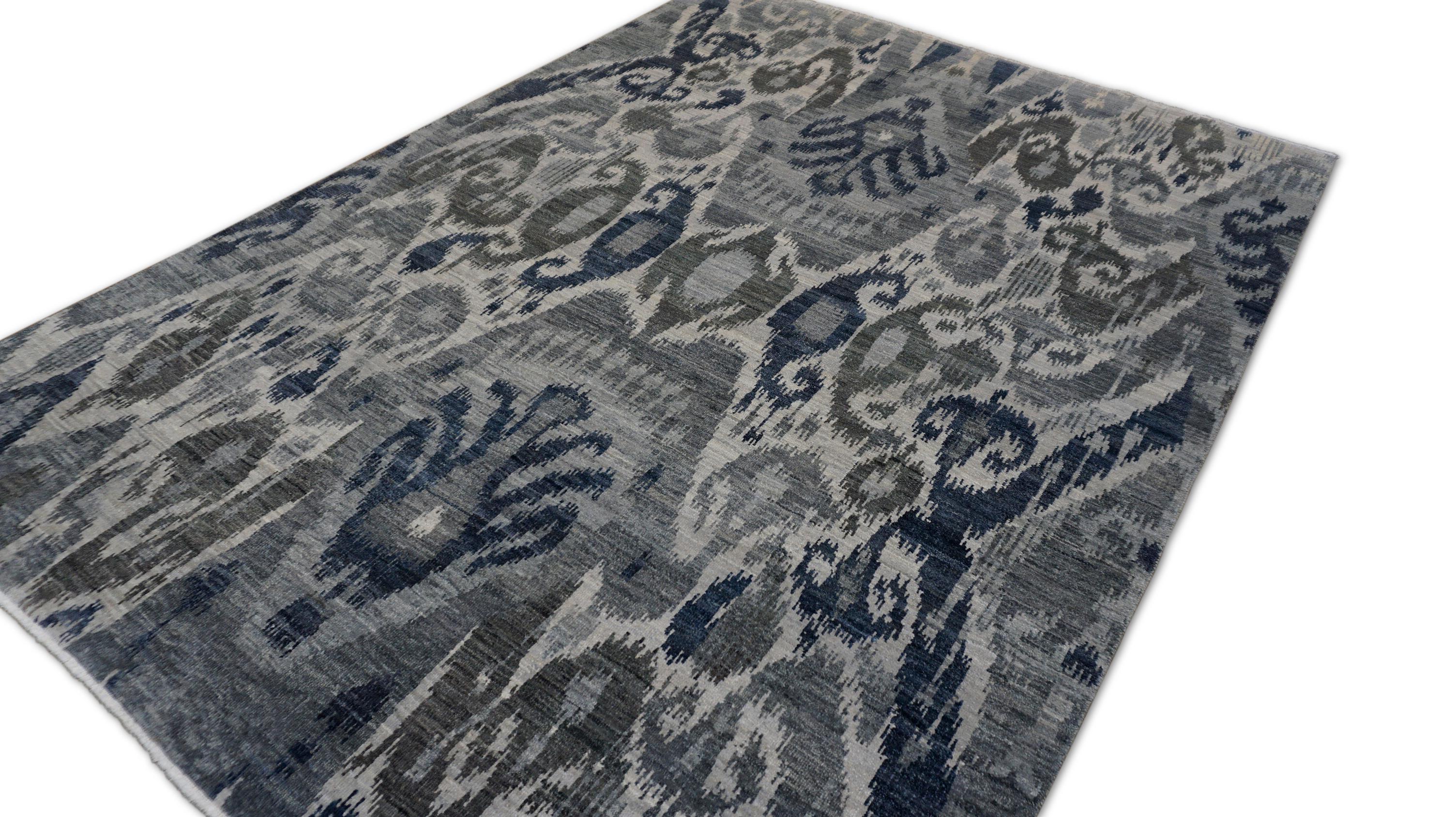 Dieser handgeknüpfte Wollteppich besticht durch sein modernes, von Ikat inspiriertes Design, das ein globales textiles Erbe mit moderner Sensibilität verbindet. Das raffinierte Muster zeigt großflächige, abstrahierte Motive in Marine-, Grau- und