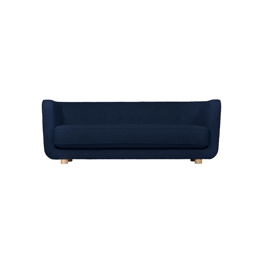 Blue and natural oak hallingdal Vilhelm sofa by Lassen.
Dimensions: W 217 x D 88 x H 80 cm. 
Materials: Textile, Oak.

Vilhelm is a beautiful padded three-seater sofa designed by Flemming Lassen in 1935. A sofa must be able to function in