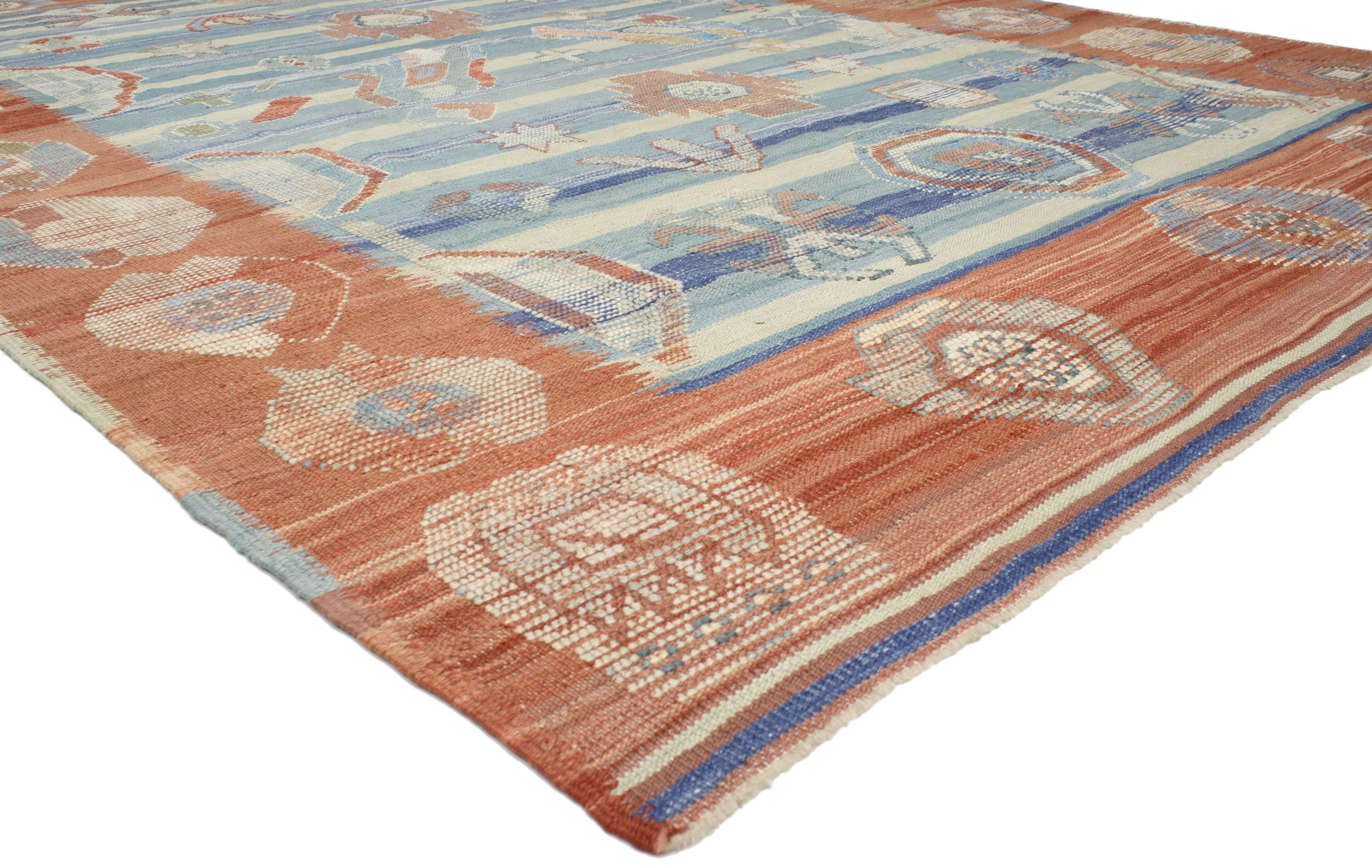 52200 blue and orange Turkish Kilim rug with tribal style. This Turkish Kilim rug has a distinctly tribal style with geometric shapes galore. The pastel orange and blue hues give it a warm, inviting feel and relaxing vibe. The design of this kilim