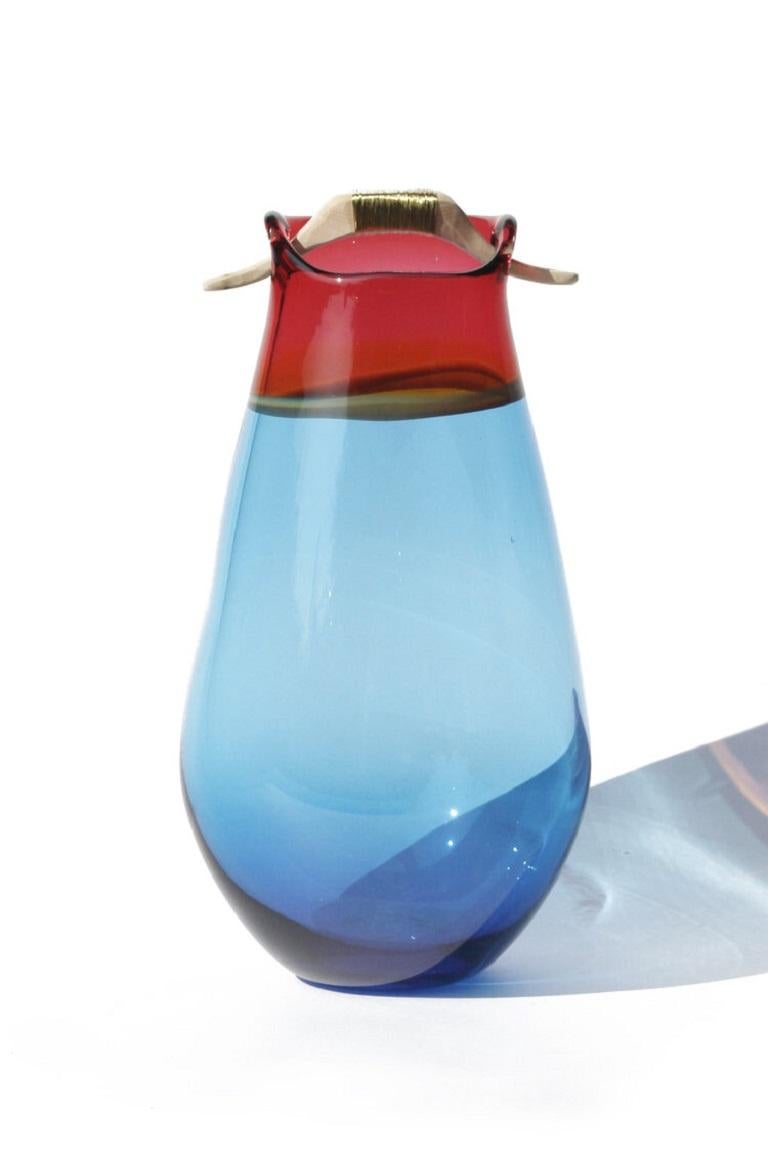 Blue and peach Heiki vase, Pia Wüstenberg
Dimensions: D 20-22 x H 32-40
Materials: glass, wood, metal wire
Available in other colors.

Inspired by a simple fix on an old sauna ladle handle, fixed with wire and outright everyday genius. Heiki