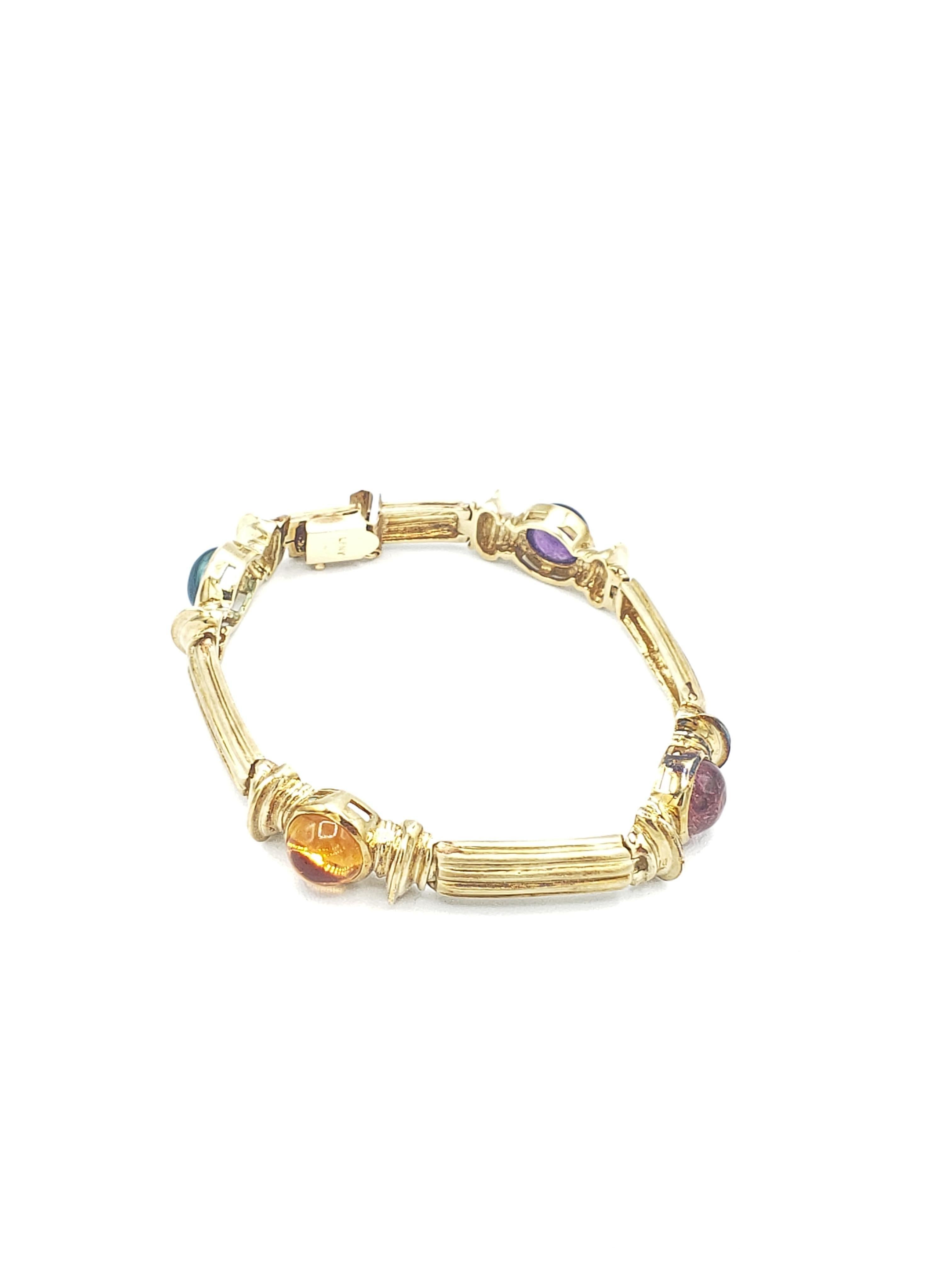Ce magnifique bracelet s'ajoute à toute collection de bijoux. Réalisé en or jaune massif 14k, il est orné de magnifiques pierres précieuses : tourmaline bleue et rose, améthyste et citrine. Le style enveloppant inspiré de la Nature lui confère une