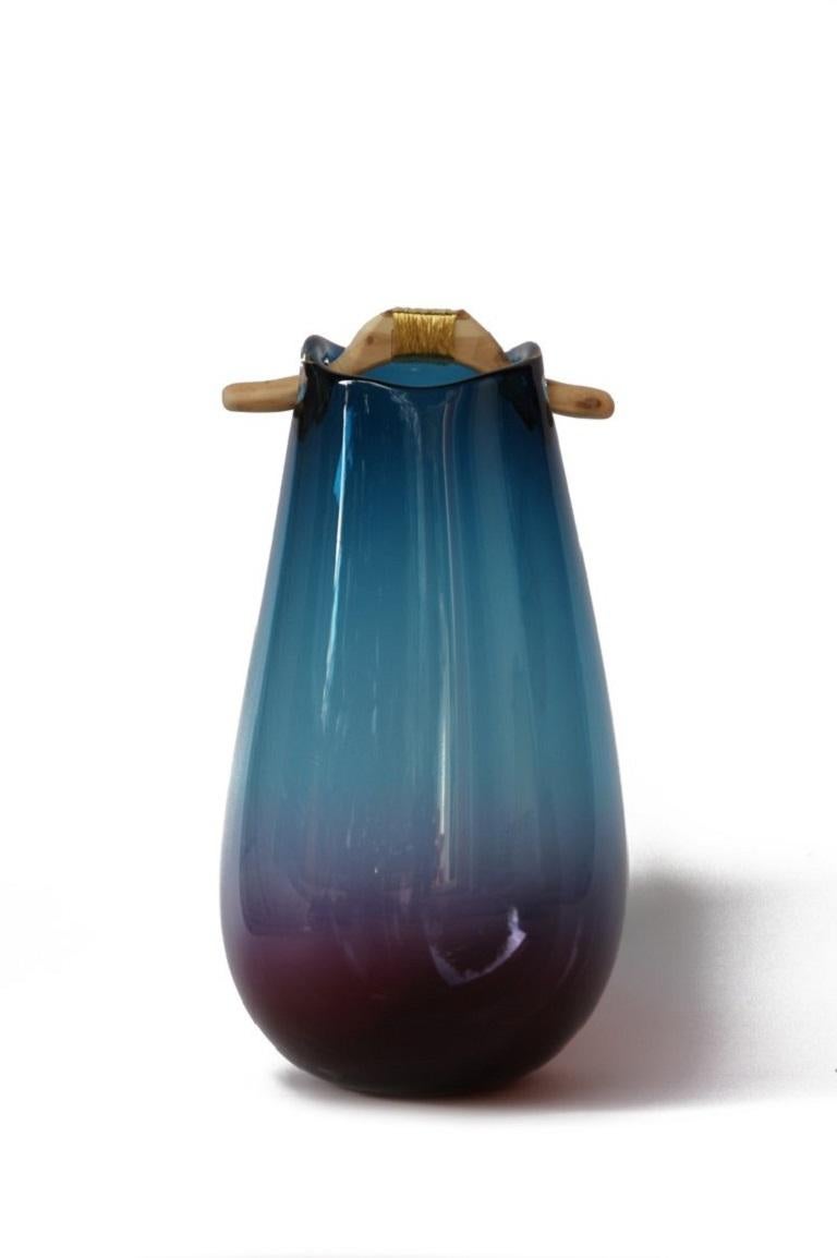Blue and Purple Heiki vase, Pia Wüstenberg
Dimensions: D 20-22 x H 32-40
Materials: glass, wood, metal wire
Available in other colors.

Inspired by a simple fix on an old sauna ladle handle, fixed with wire and outright everyday genius. Heiki