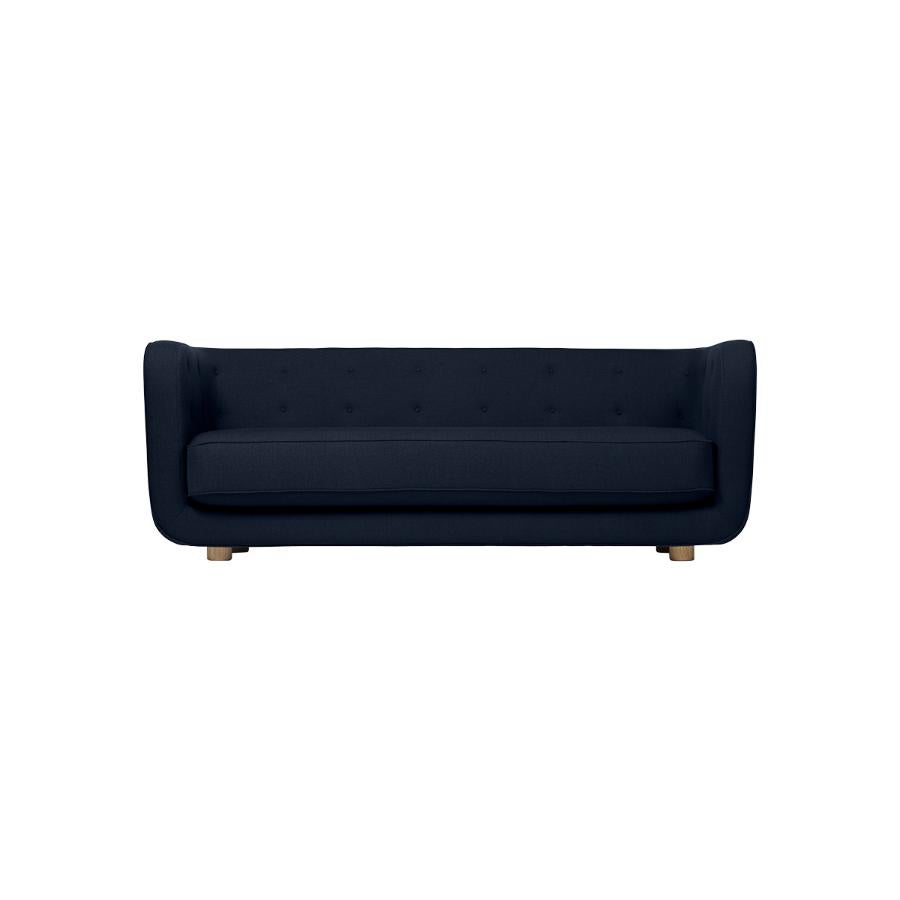 Blue and smoked oak Raf Simons Vidar 3 Vilhelm sofa by Lassen.
Dimensions: W 217 x D 88 x H 80 cm. 
Materials: Textile, Oak.

Vilhelm is a beautiful padded three-seater sofa designed by Flemming Lassen in 1935. A sofa must be able to function in