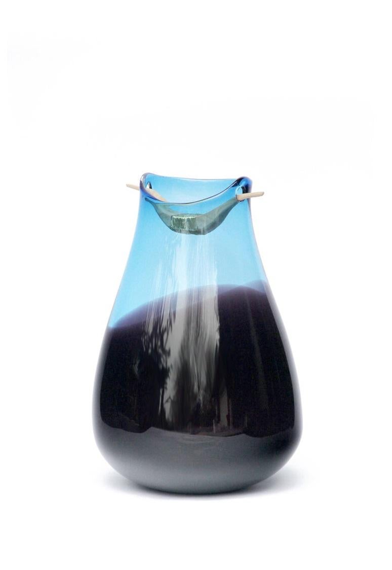 Vase Heiki bleu et topaze, Pia Wüstenberg
Dimensions : D 20-22 x H 32-40
MATERIALES : verre, bois, fil métallique.
Disponible dans d'autres couleurs.

Inspiré d'une simple réparation d'un vieux manche de louche de sauna, fixé avec du fil de fer et