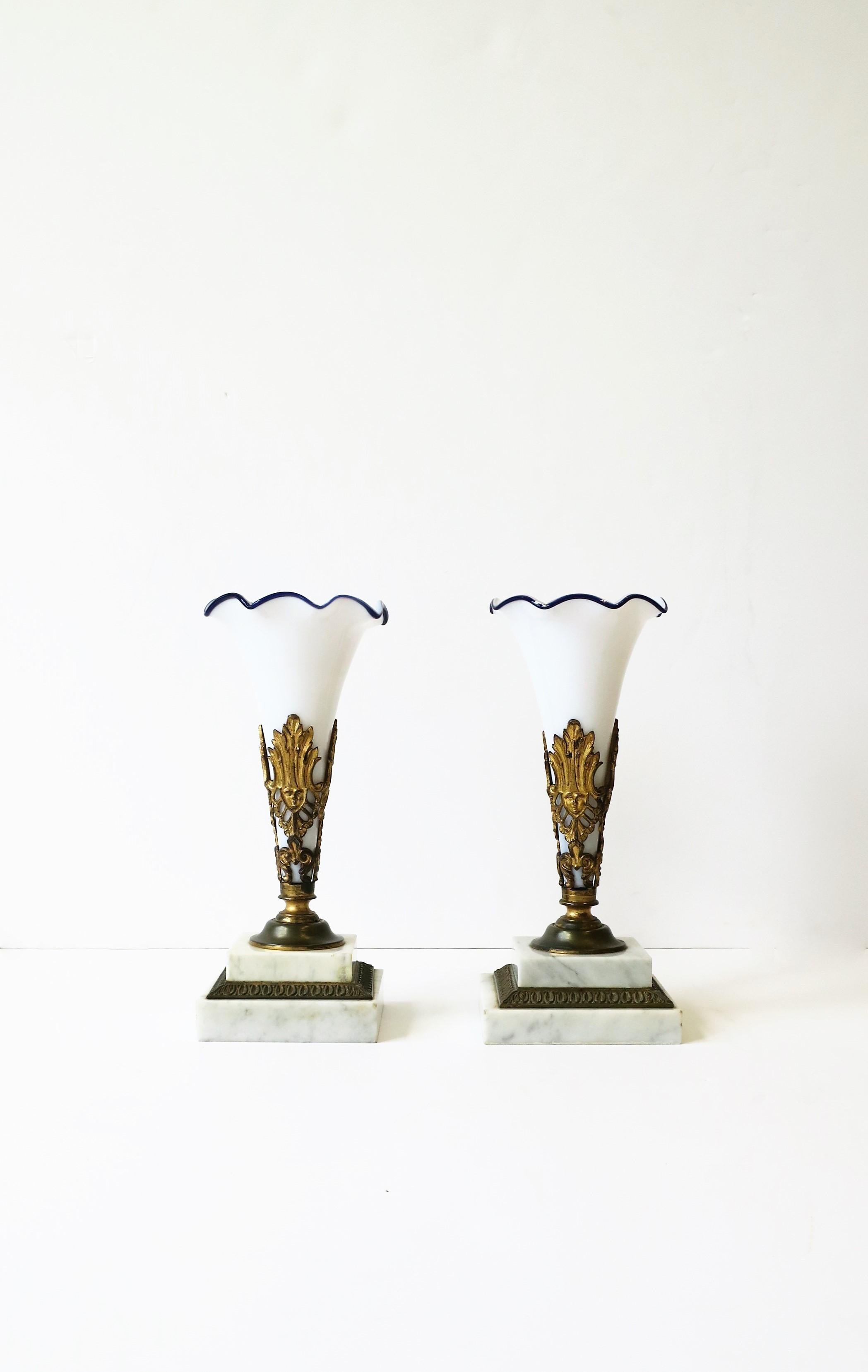 A beautiful and substantial pair of French white and blue art glass vases on gold gilt bronze/brass and white marble bases, circa early-20th century, France. The white art glass vases are hand-blown, edge has a wave design with blue art glass detail