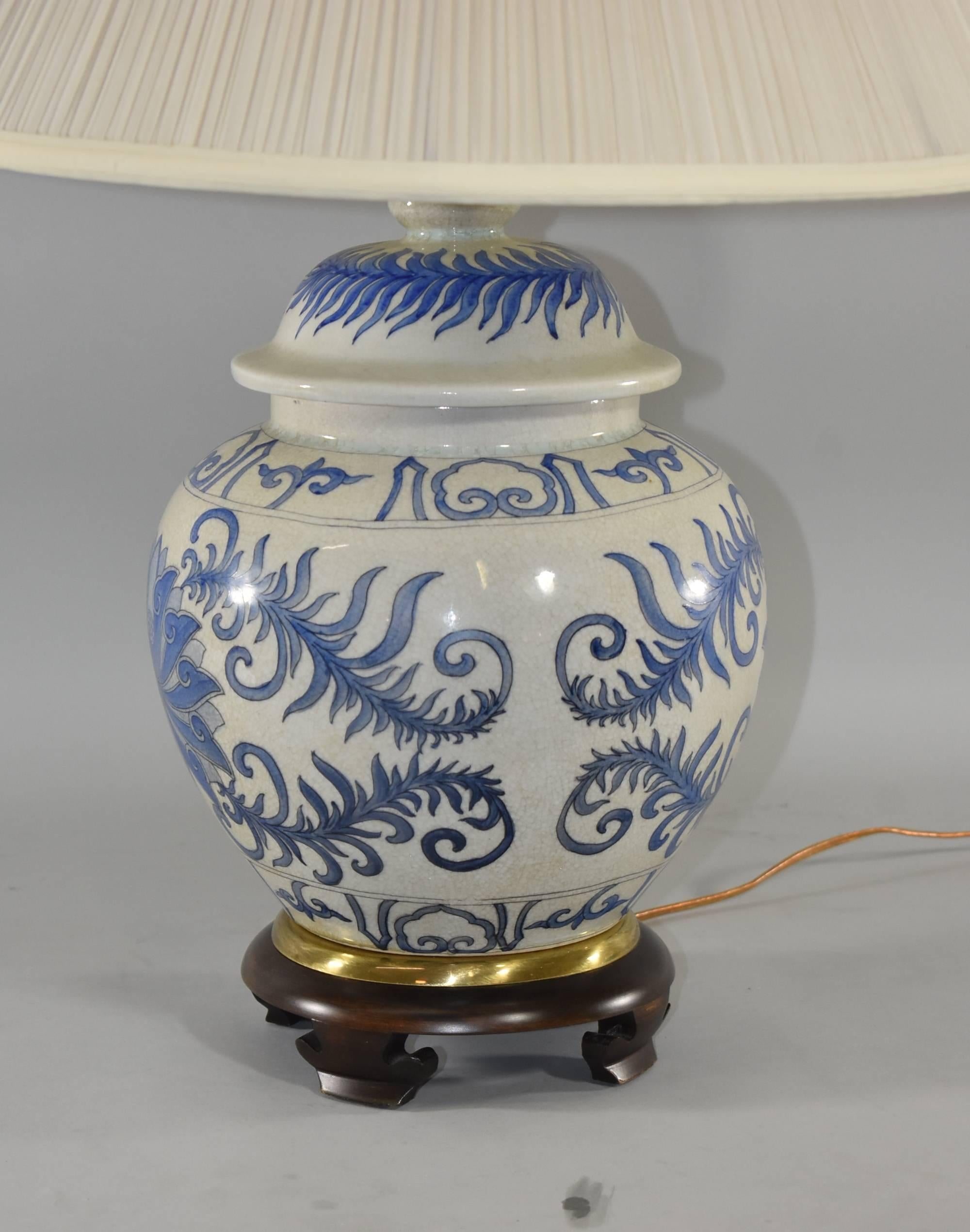 An eye-catching Asian Style ginger jar lamp by Frederick Cooper. It features a blue and white body with leaf detail and a carved wood base. The original Frederick Cooper label is attached.