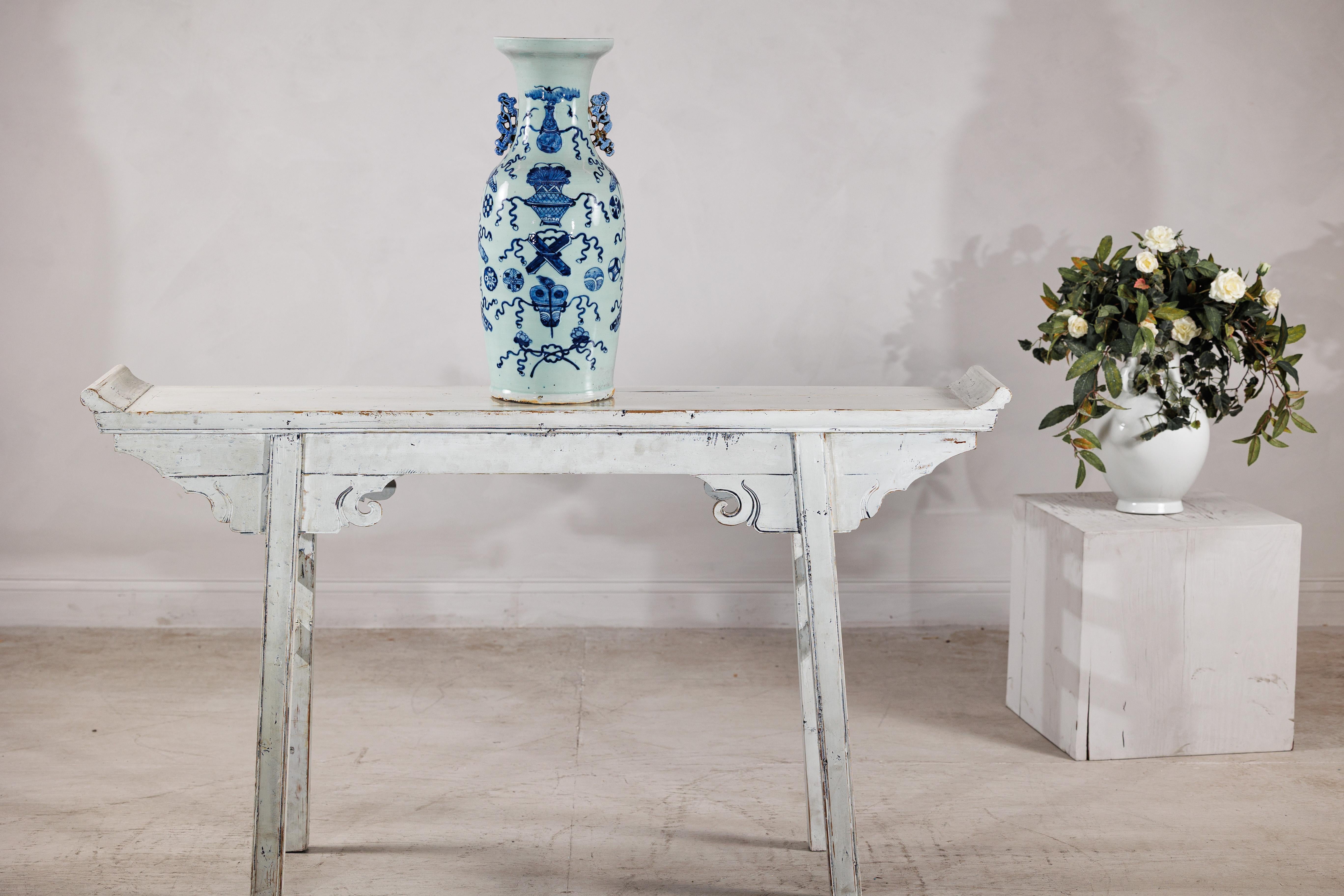 Un elegante vaso da altare cinese in bianco e blu con oggetti di buon auspicio resi in un profondo blu cobalto su un fondo leggermente color celadon. La forma alta e slanciata si innalza fino a un bordo svasato (misura 7