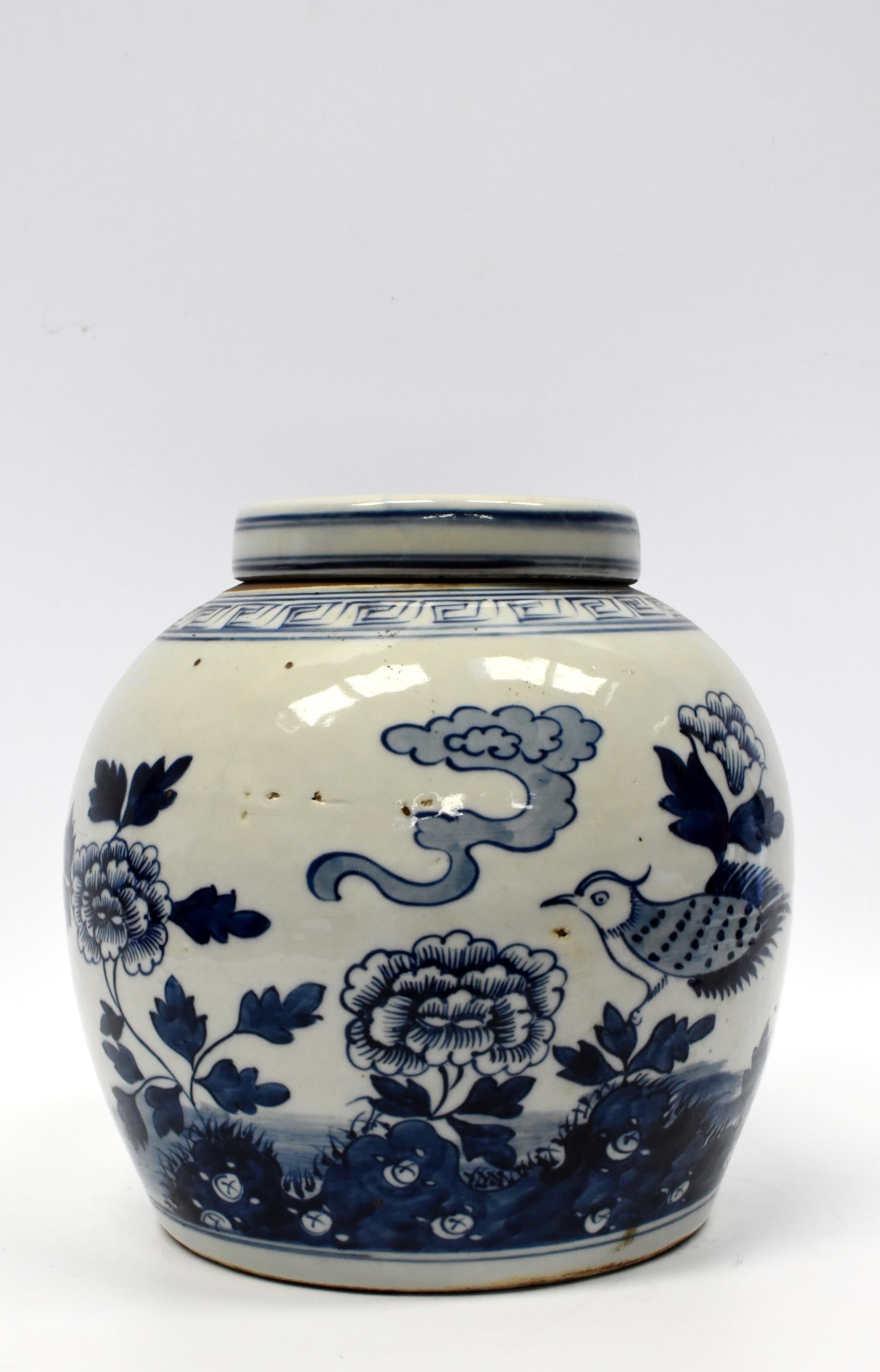 A beautiful 20th century Chinese blue and white ginger jar depicting a bird resting on top of a plant of peony. A ring of eternity scrolls decorate the area near the opening. Images are hand-painted. Bird symbolizes joy and peony good fortune. The