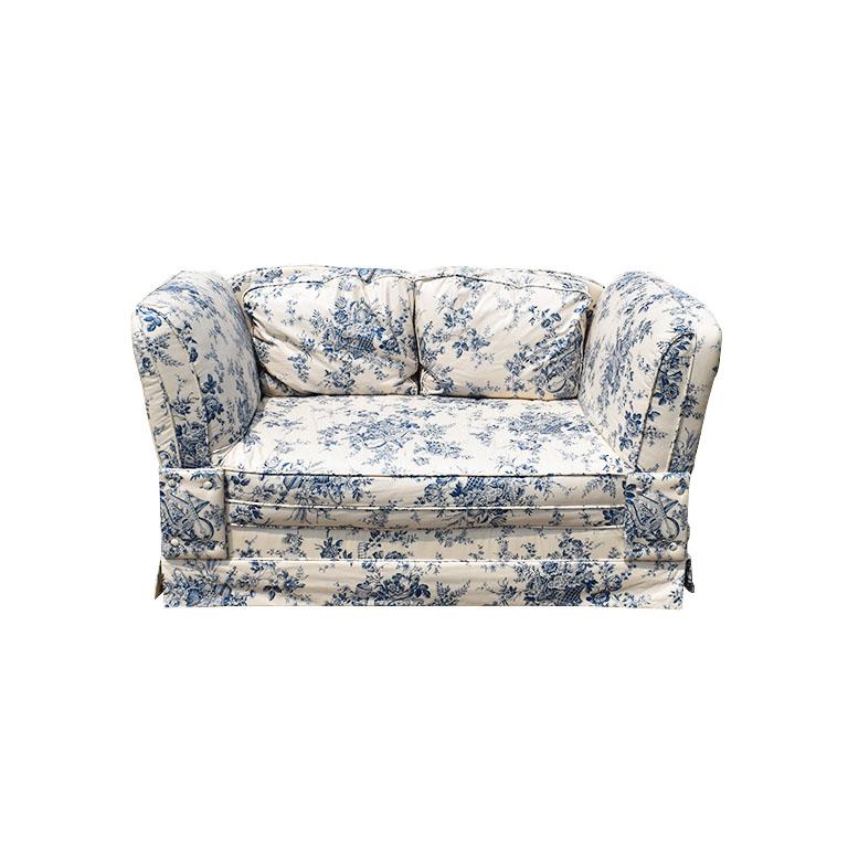 A beautiful and very unique loveseat with adjustable sofa arms. This wonderful piece seats two and is covered in a blue and white floral fabric. Each arm folds down to create a different and more modern look. This piece was originally covered in