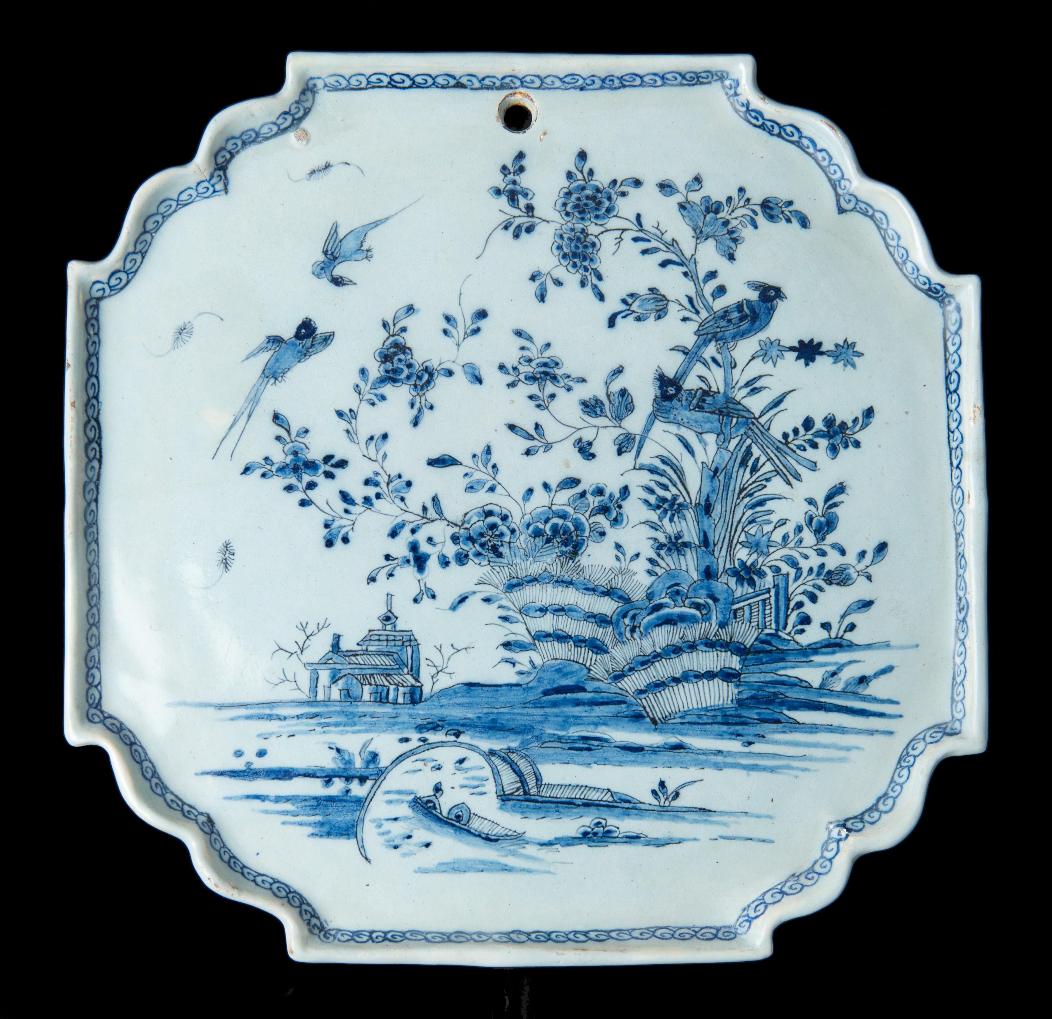 Blue and white chinoiserie plaque. Delft, 1740-1760.

This octagonal plaque has a thin, straight, upright rim with indented accolade-shaped corners, which is decorated on the inside with a continuous scroll ornament. The plaque is painted in blue