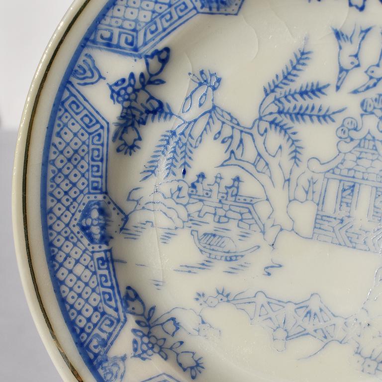 Set of 4 blue and white saucer plates. 

Each plate features a painted scene of a pagoda, set atop a hill surrounded by flora and fauna. Birds fly above the pagoda, Japanese men in costume walk in the background and fern and willow trees flank the