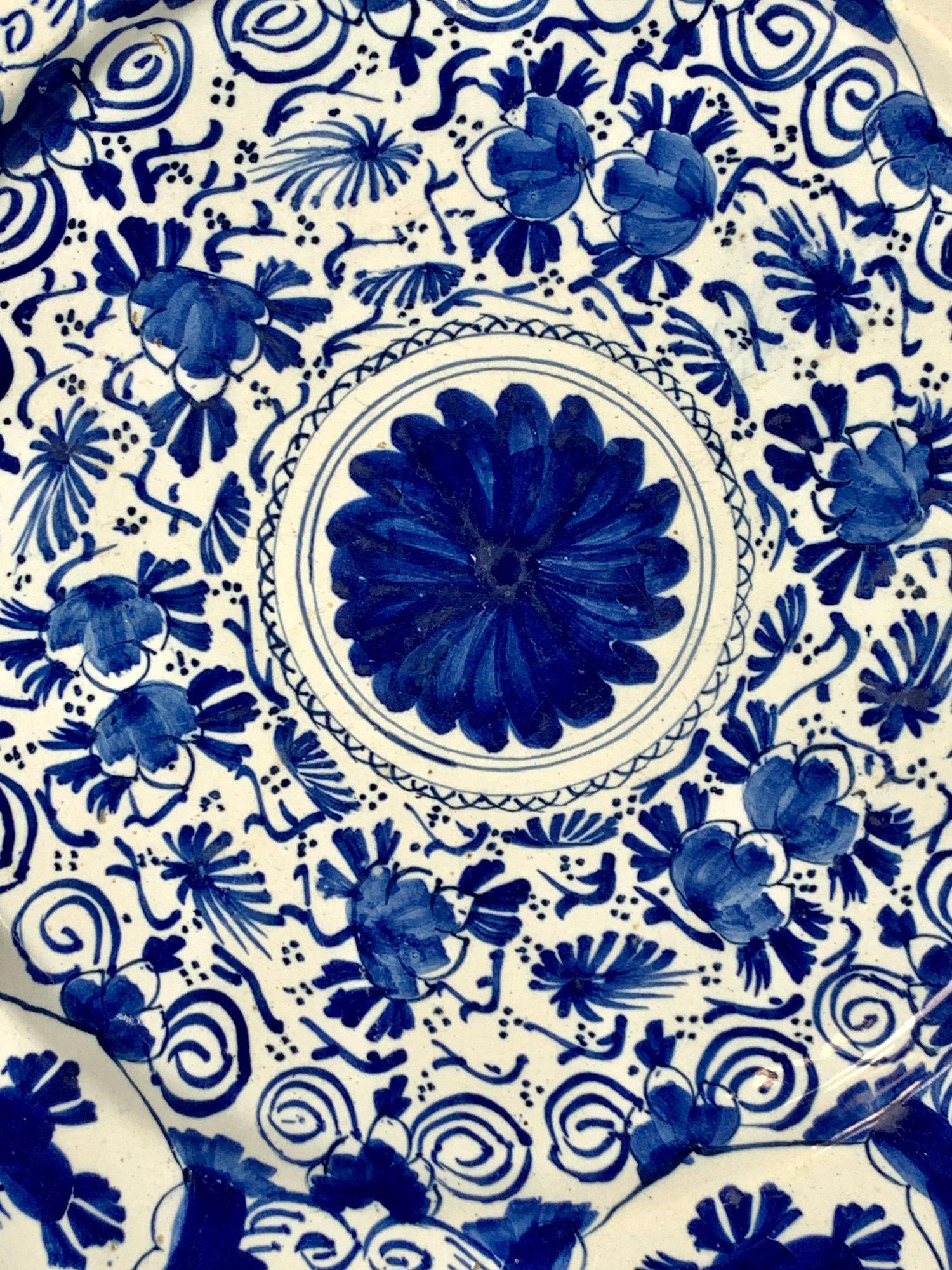 This beautiful blue and white Dutch Delft charger was hand-painted circa 1770.
The center of the charger is decorated with a large cobalt blue flower.
Beyond the center, we see two circles of tulip buds, leaves, and scrolling vines.
The vibrant
