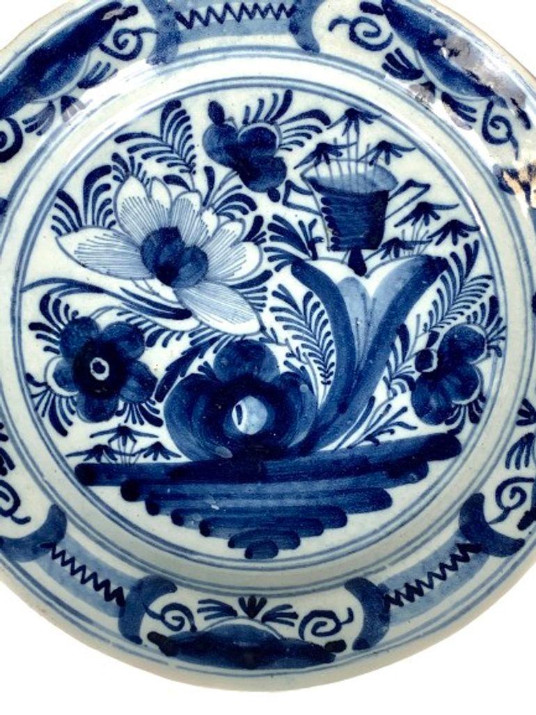 Hand Painted in the Netherlands circa 1800, this antique blue and white Dutch Delft charger has beautiful cobalt blue coloring.
The center shows a garden scene with large flowers, rockwork, and an open basket.
The shades of cobalt blue is splendid