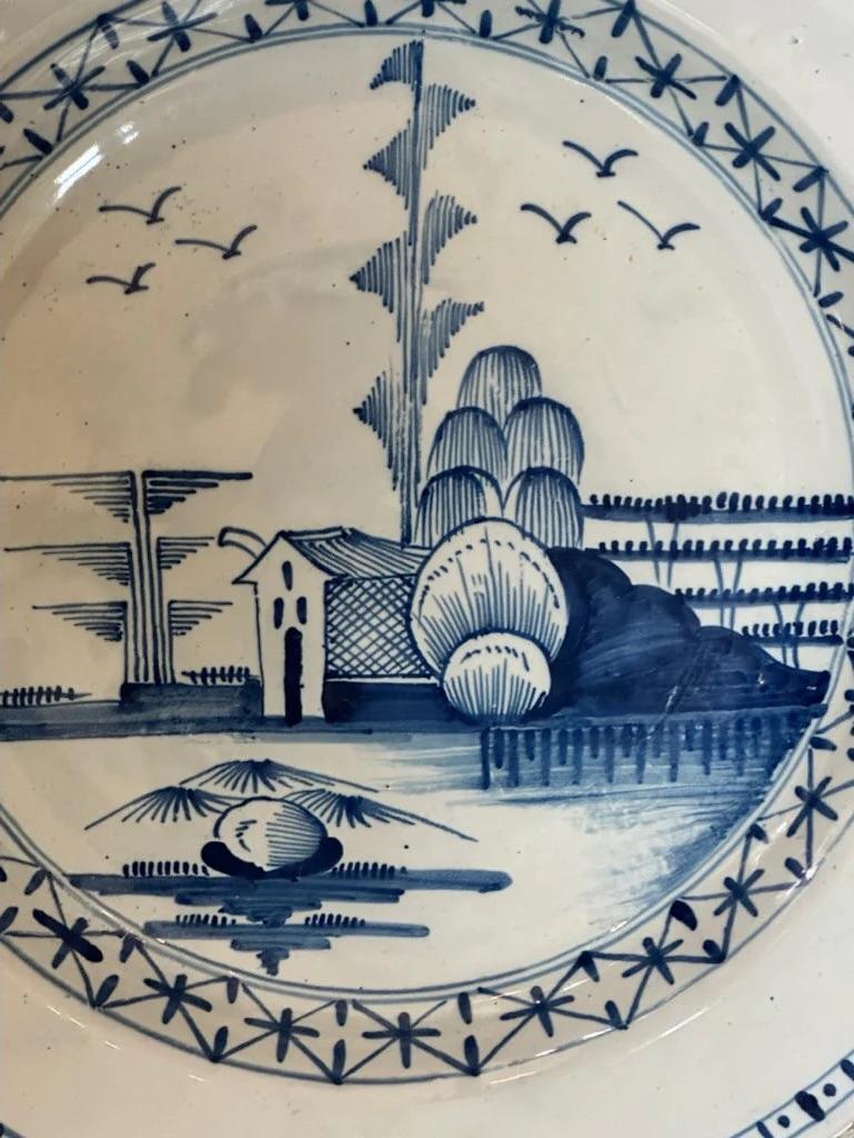 Delft charger, London, painted in blue with a house in a stylized landscape, 18th Century.  diam. 14.25 in.
