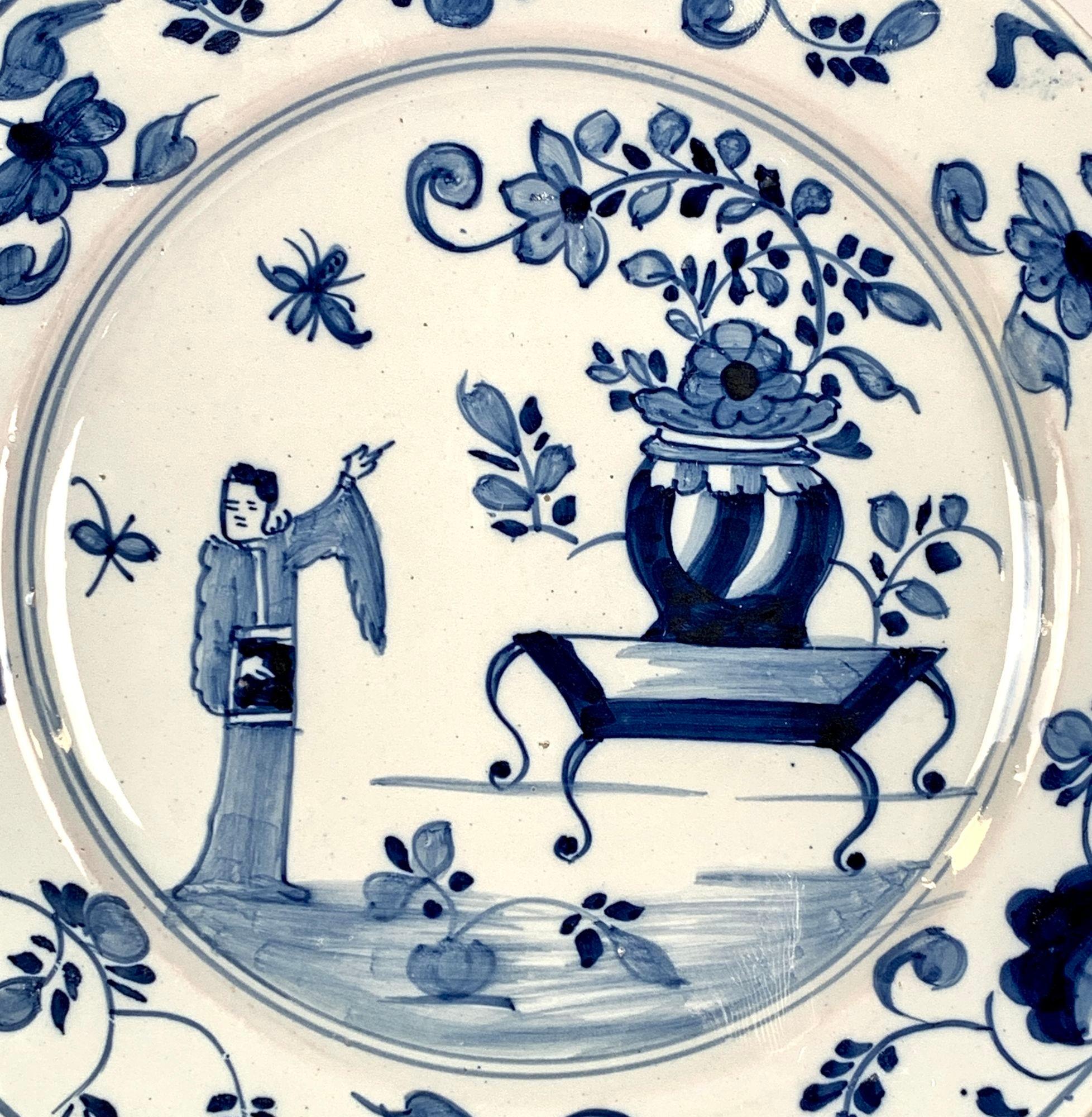 This stunning blue and white Delft dish was hand painted in England around 1760.
It features a charming chinoiserie scene, where an Oriental figure is pointing towards a vase while two butterflies flutter nearby.
It seems as though she is signaling