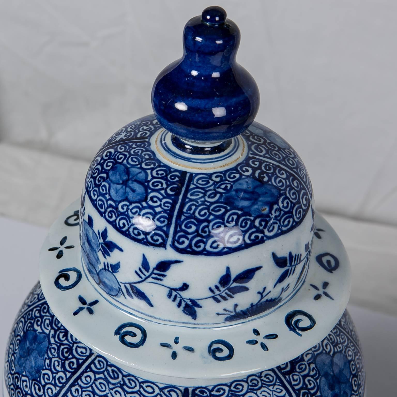 This Dutch Delft blue and white antique mantle jar is hand painted in a deep cobalt blue. 
The pot is decorated all around with sprays of chrysanthemums. 
The top, shoulders, and base are painted with scrolling vines and flower heads.
Made in The