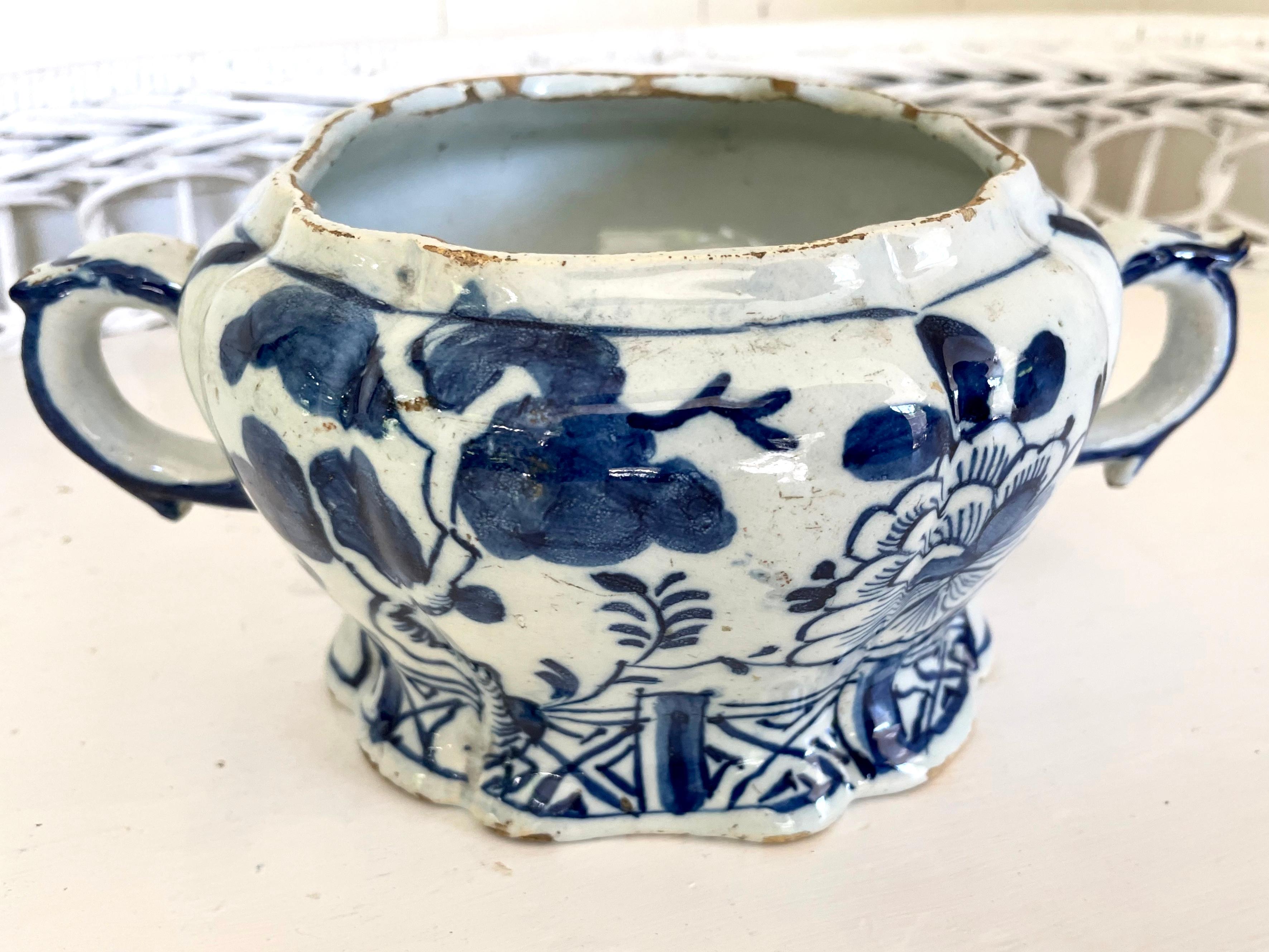 Blue and white Delft handled chinoiserie vase. Antique Dutch porcelain vase with rich blue flowers and chinoiserie fencing in a lustrous glaze; with scrolled handles at side on shaped footed base. Cracks in base and small chips do not detract from