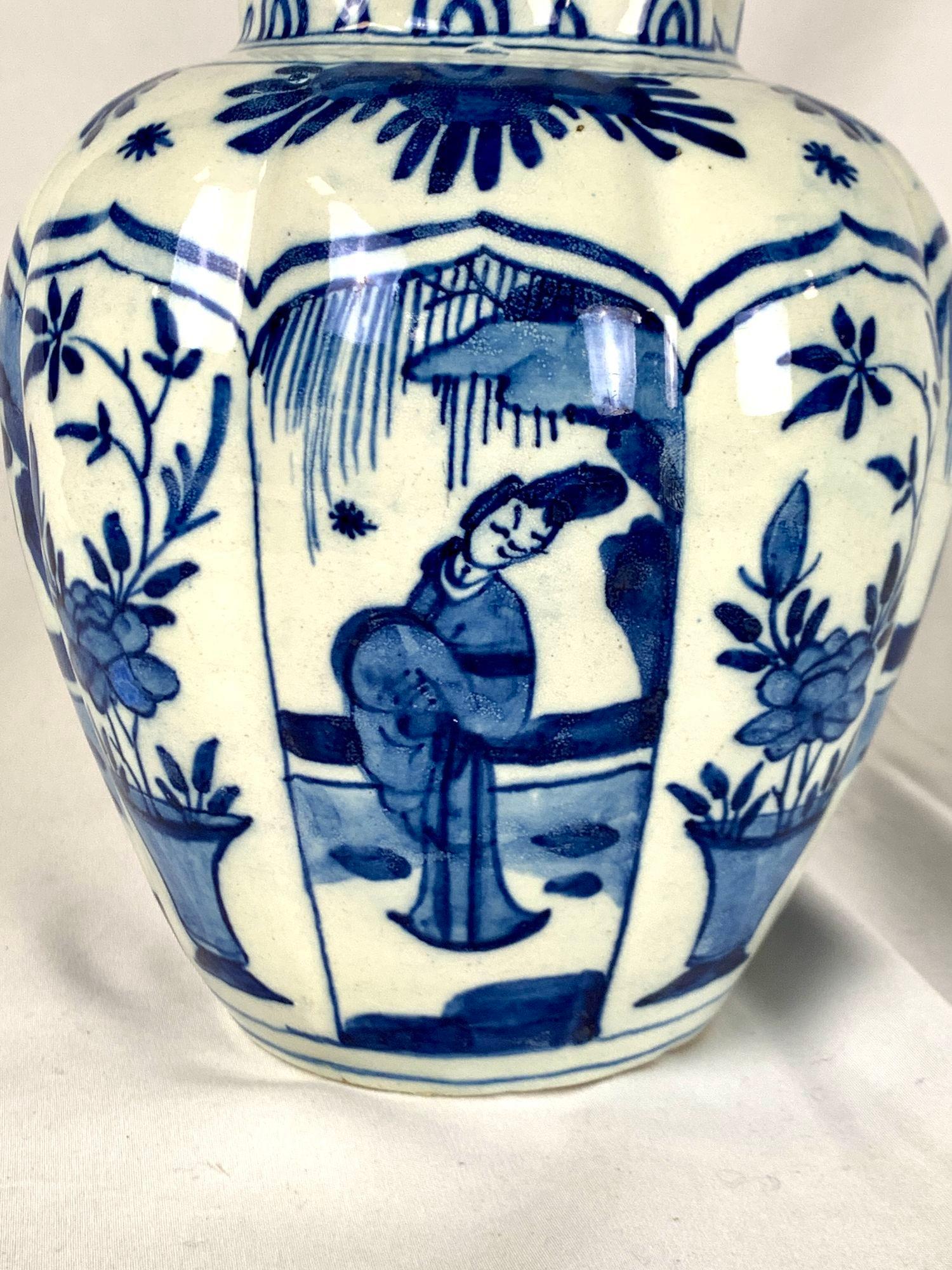 This beautiful jar was hand painted in the Netherlands around 1800.
It is decorated with a blue and white chinoiserie pattern that features alternating ogival panels with Oriental figures and vases containing peonies.
The jar is lobed in an