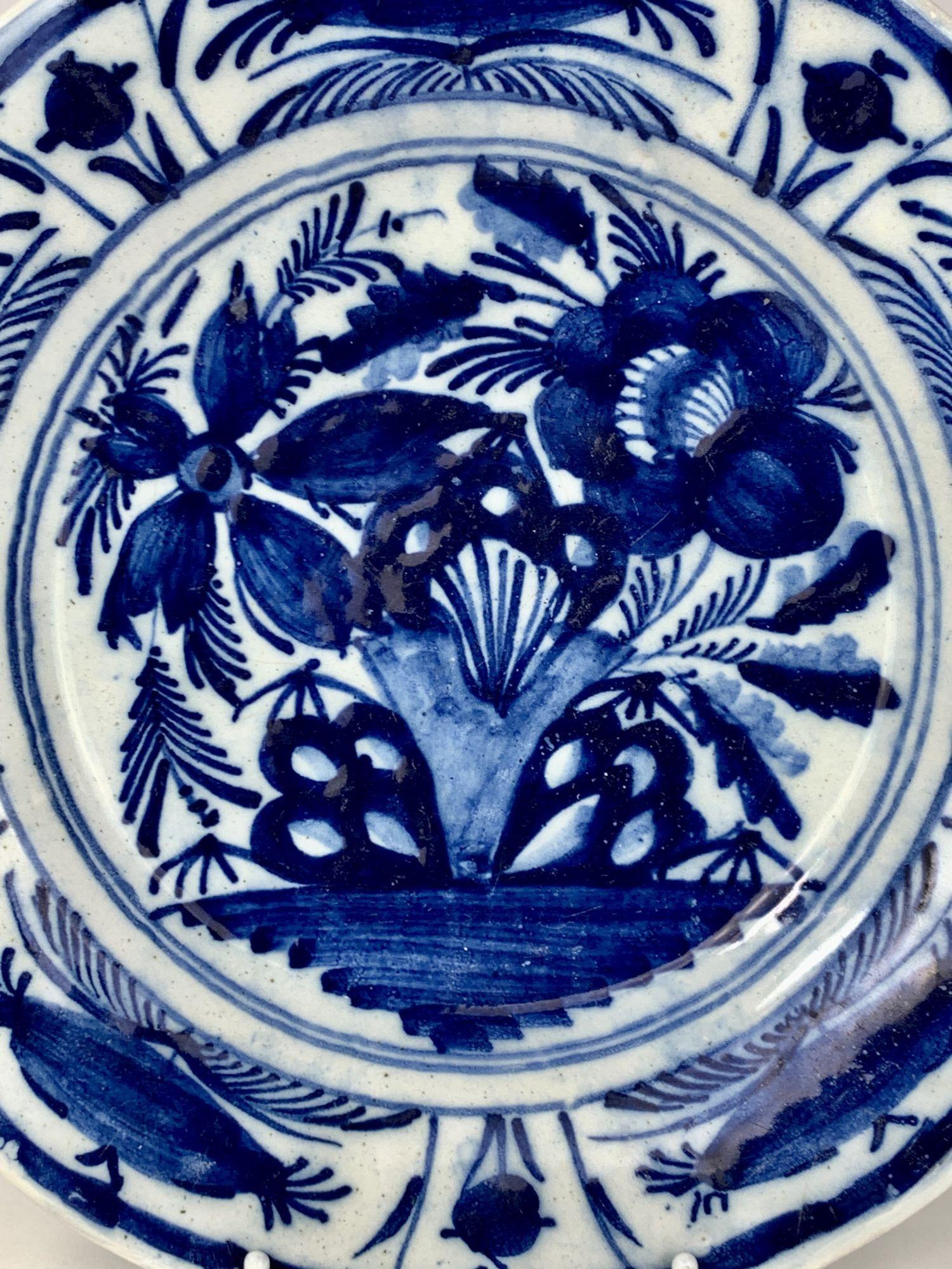This lovely Delft plate is hand-painted in deep cobalt blue. 
Made in the Netherlands circa 1800, it shows flowers bursting into view. 
The border is decorated with panels depicting buds and flowers.  
This Delft plate is a beautiful example of