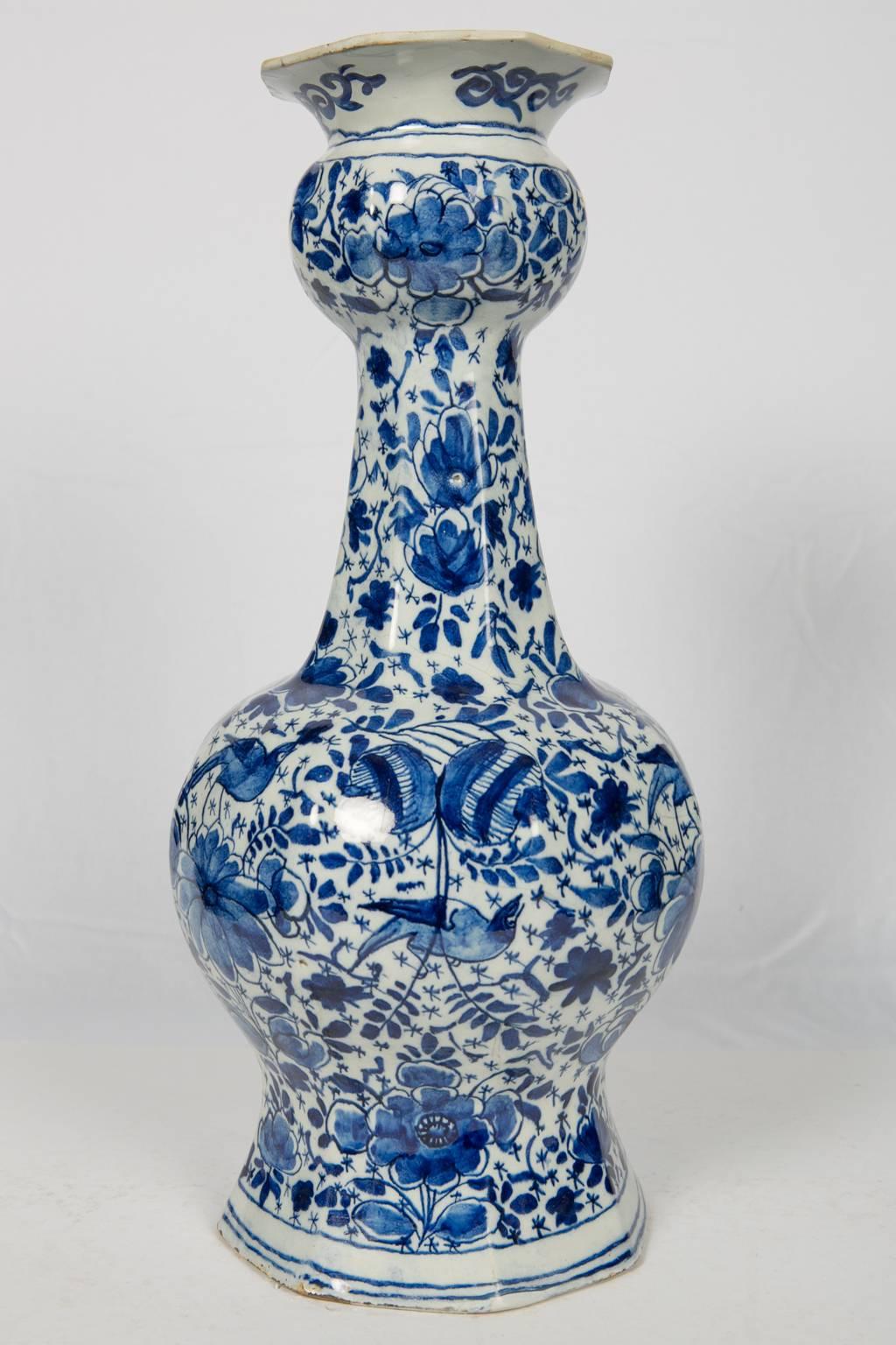 A tall 18th century Blue and White Dutch Delft bottle vase hand-painted with a lovely all around pattern of songbirds among large flowers and scrolling vines. Made circa 1780, the vase is hand-painted in deep cobalt blue. The octagonal design was