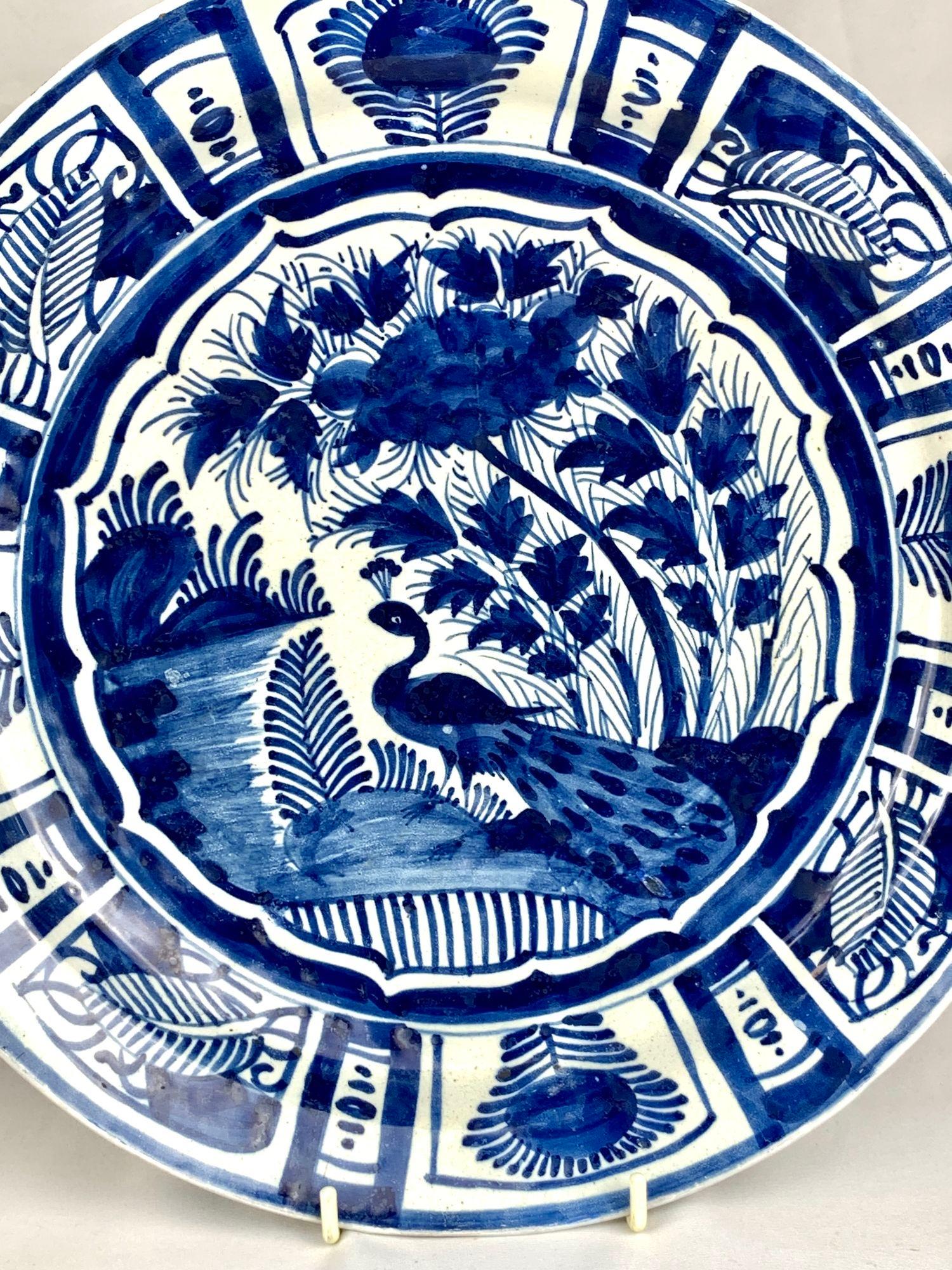 This mid-18th-century Dutch Delft charger is handpainted in several shades of cobalt blue.
The viewer is drawn to the lovely scene in the center, which shows an elegant peacock in a flowery garden near water.
The wide rim has eight panels, each with