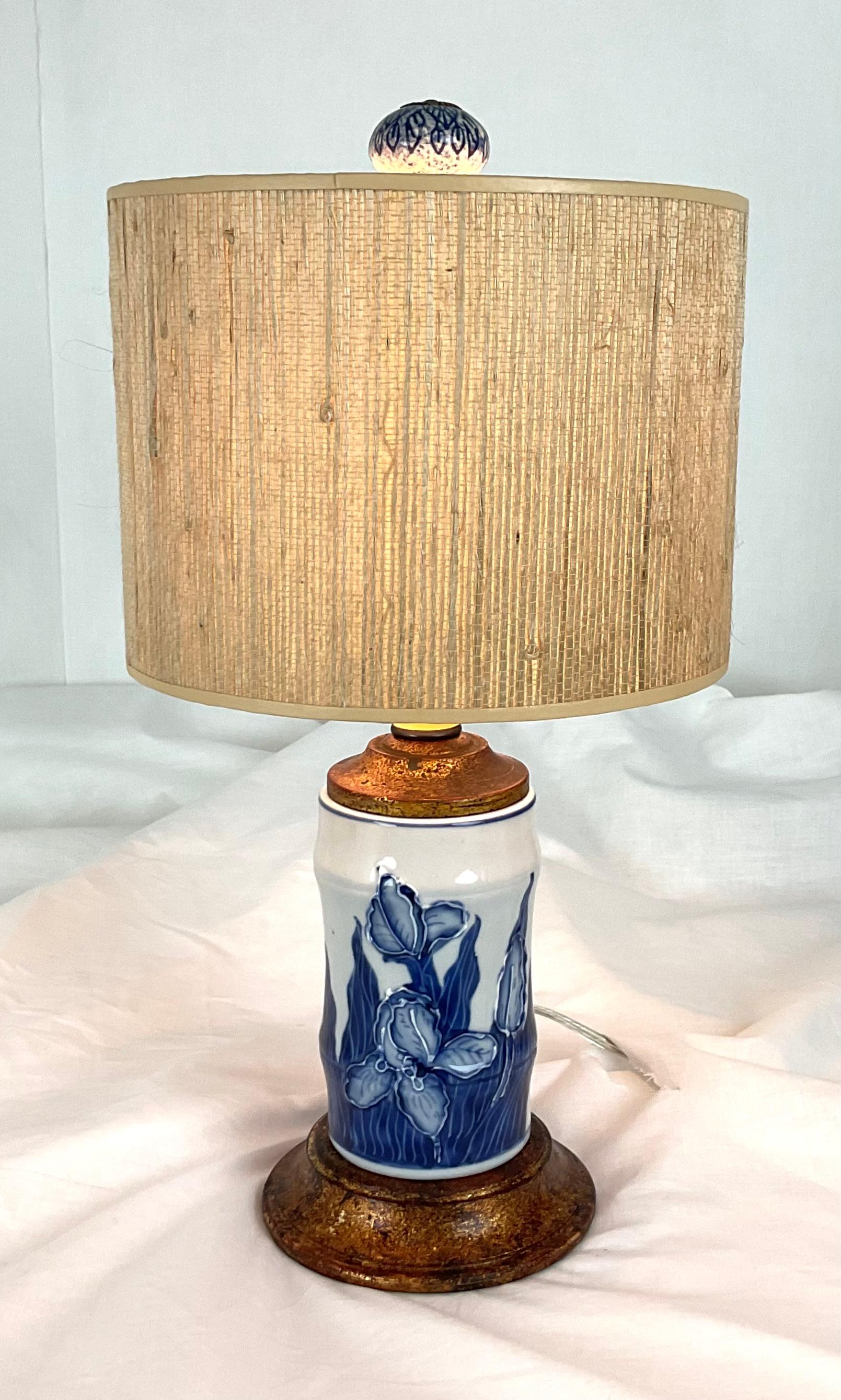 This elegant vintage table lamp combines timeless craftsmanship with classic blue and white artistry. The porcelain base features beautifully hand-painted iris flowers in deep cobalt blue, set against a crisp white glaze. A warm, patinated brass