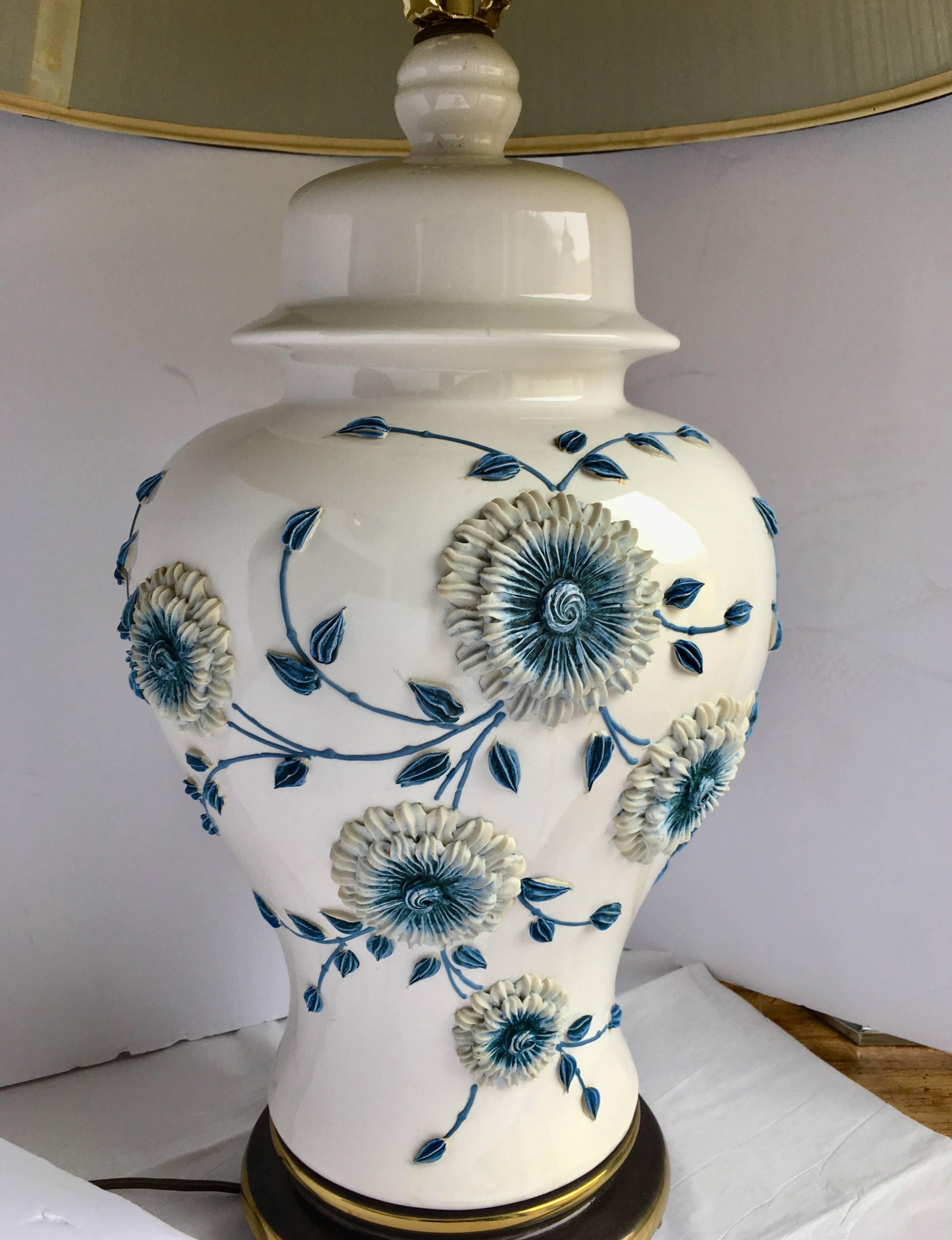 Midcentury blue and white/cream glazed porcelain table lamp featuring a hand applied floral relief design mounted on a brass bass. Lampshade not included.
