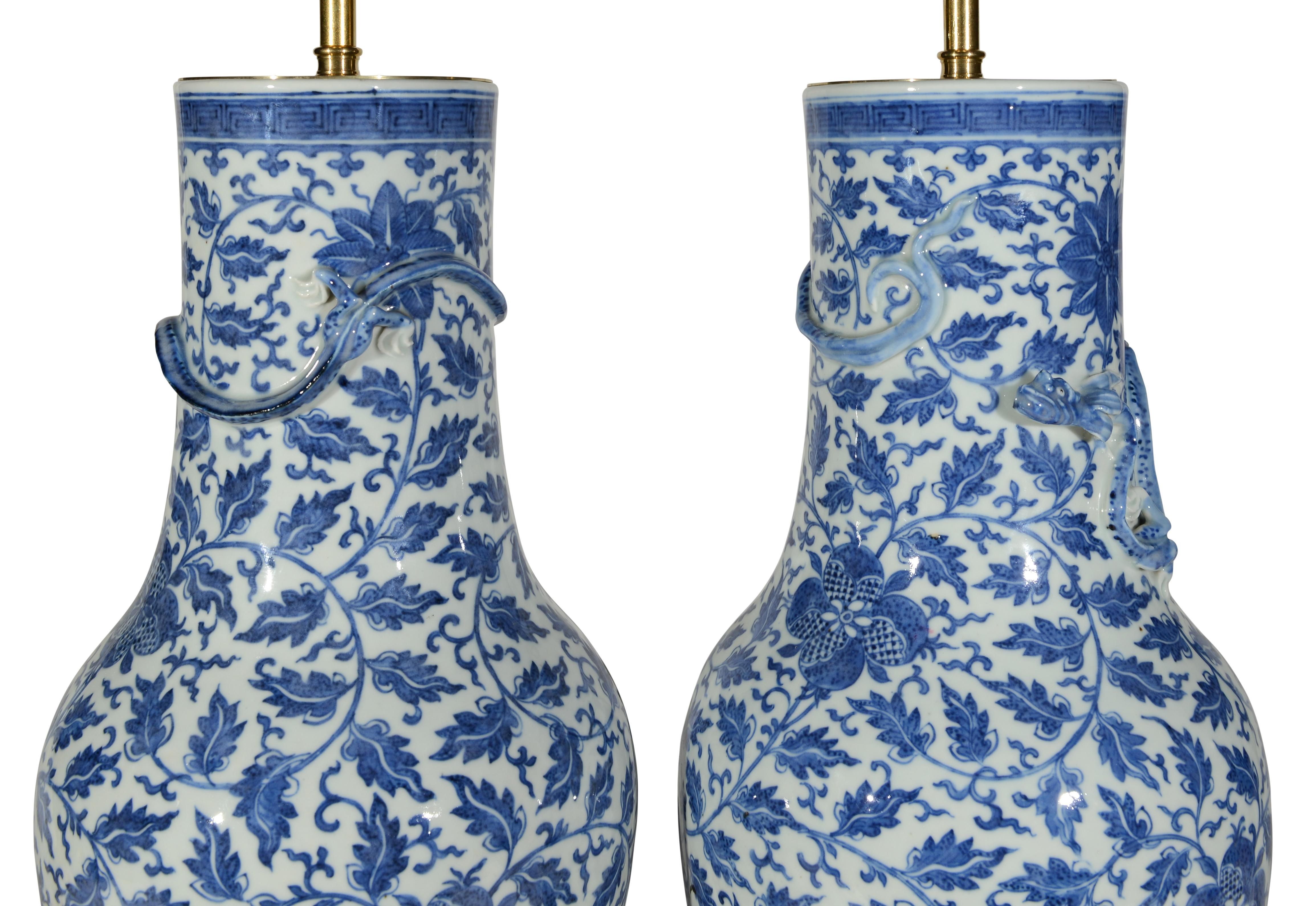 Paire de vases en porcelaine chinoise du XIXe siècle, décorés de feuillages stylisés et de gerbes de grenades dans des tons bleus sur fond blanc, chacun avec un Chilong encrassant le col, montés sur table.
lampes avec des bases dorées à la