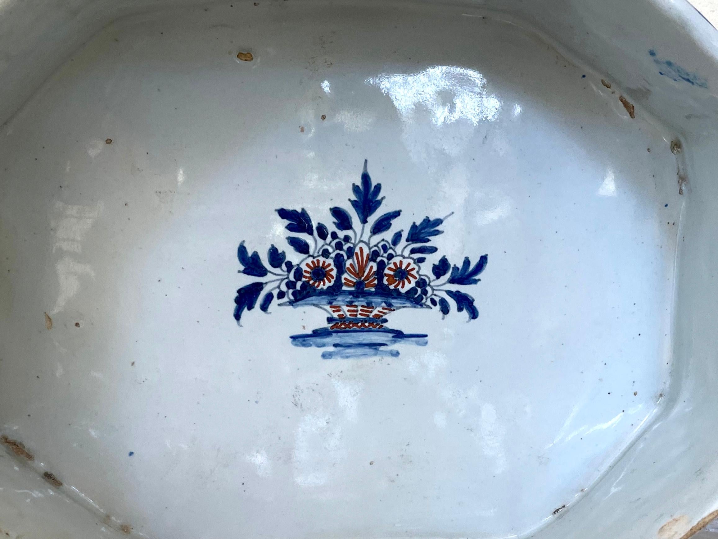 Blue and white glazed French terracotta compote. Antique low handled fruit basket compote serving piece with blue and iron red floral sprays, diapering and central floral basket all raised on three small feet. France, late 18th century.