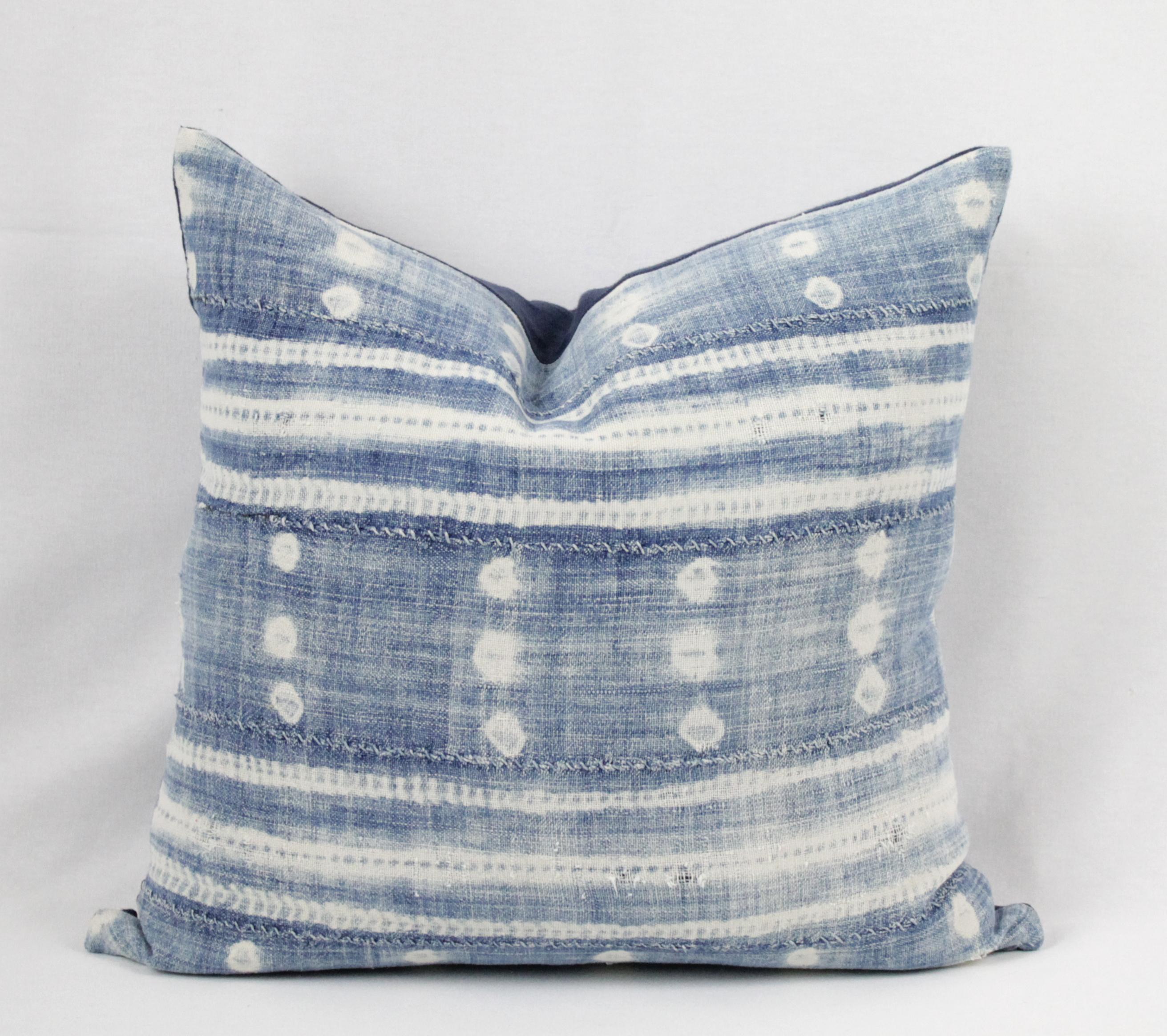 Blue and white batik style pillow, with zipper closure. Pillow has horizontal exposed seams with some distressing and fading. Pillow is lined with an indigo blue linen. Back is in an indigo blue linen and finished with overlocked edges. Main colors