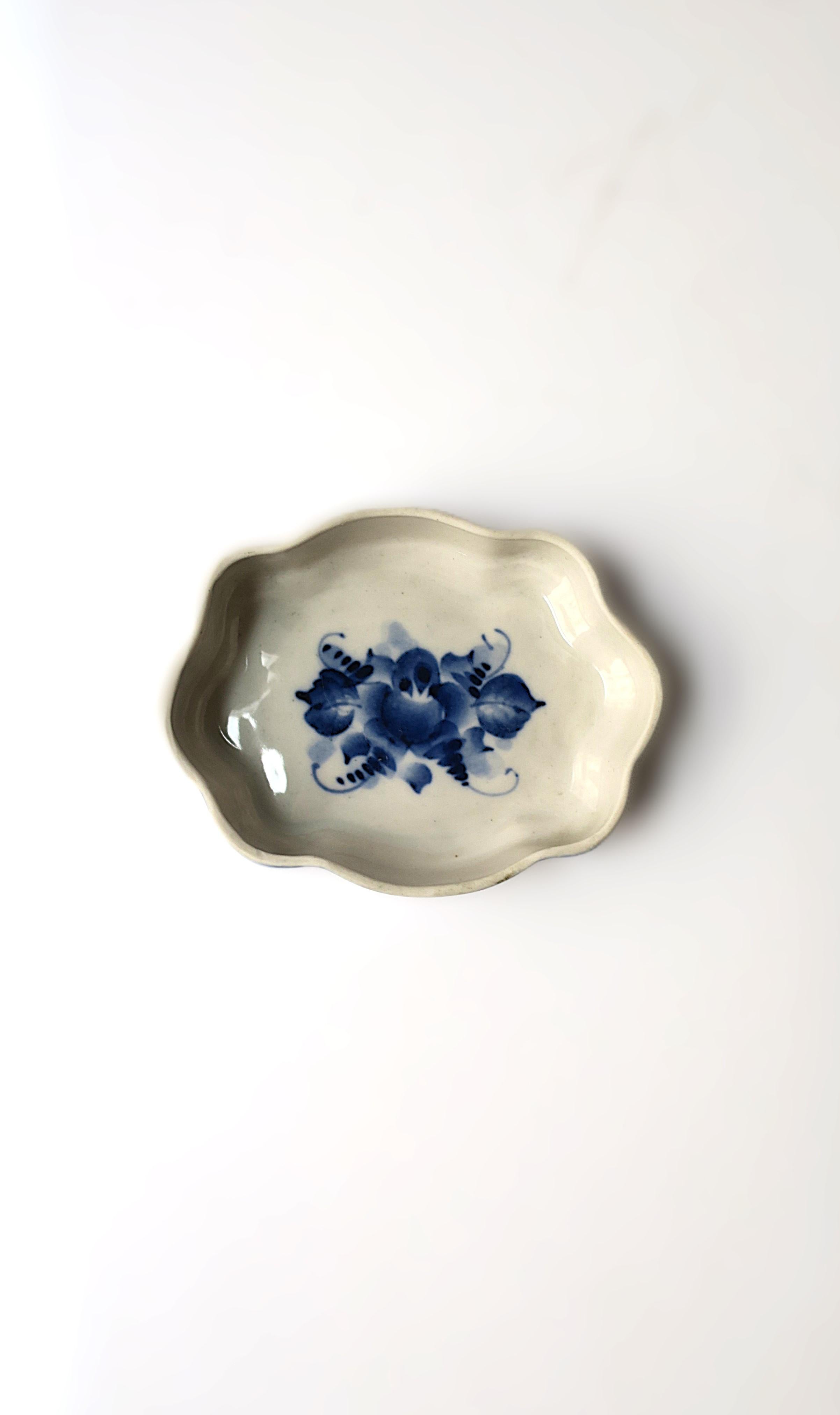 A blue and white (stone-white) jewelry dish with hand-painted floral and leaf design and scalloped edge, in the Rococo design style, hand-made, signed by artist, circa late-20th century. A blue and stone-white oval jewelry dish with scalloped edge,
