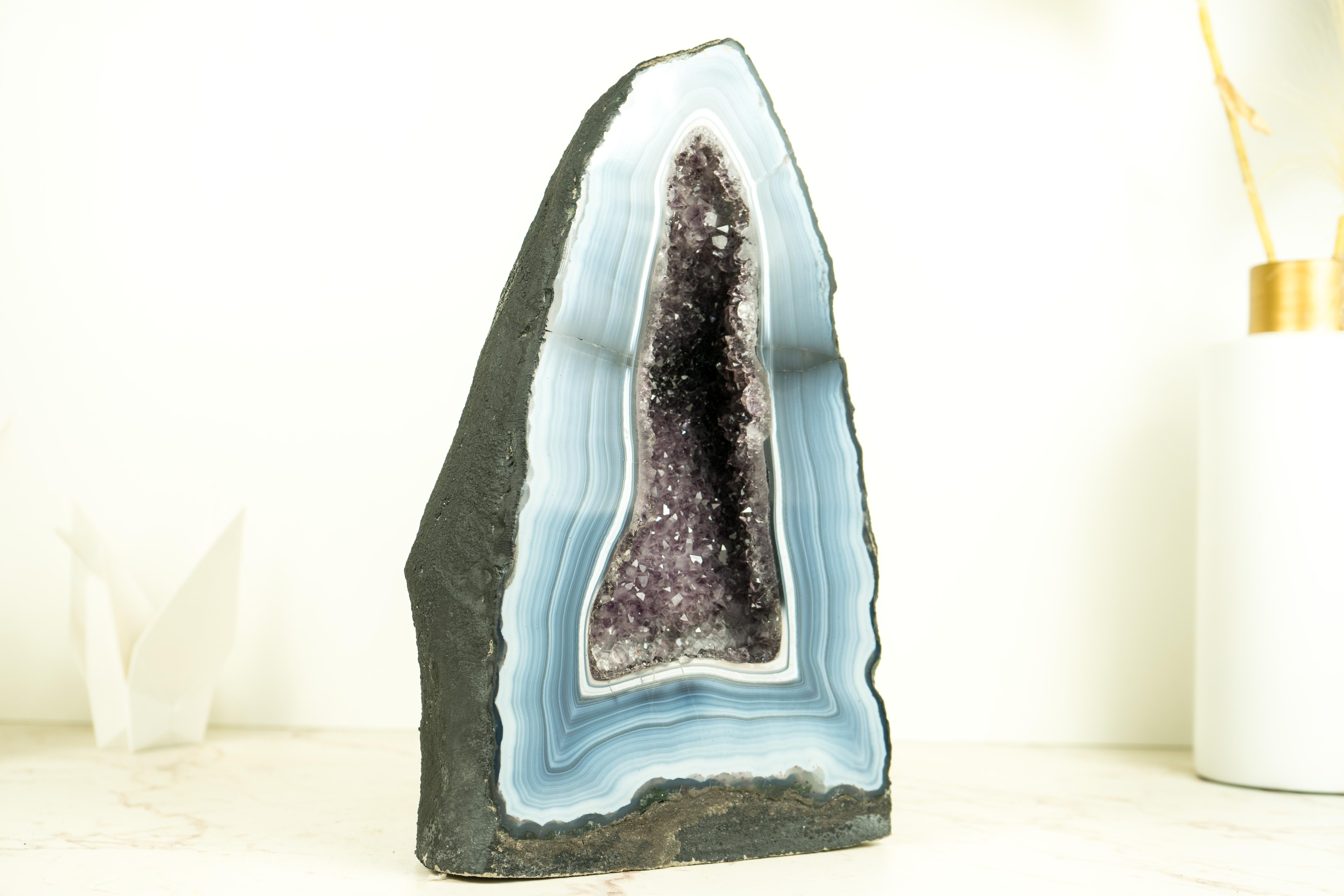 Raro geode di agata blu a strisce con cristallo di ametista druzy: un capolavoro di agata

▫️Description
Una delle geodi di agata più artisticamente belle che si siano mai viste, questa cattedrale di agata blu e bianca presenta dei lacci a strisce