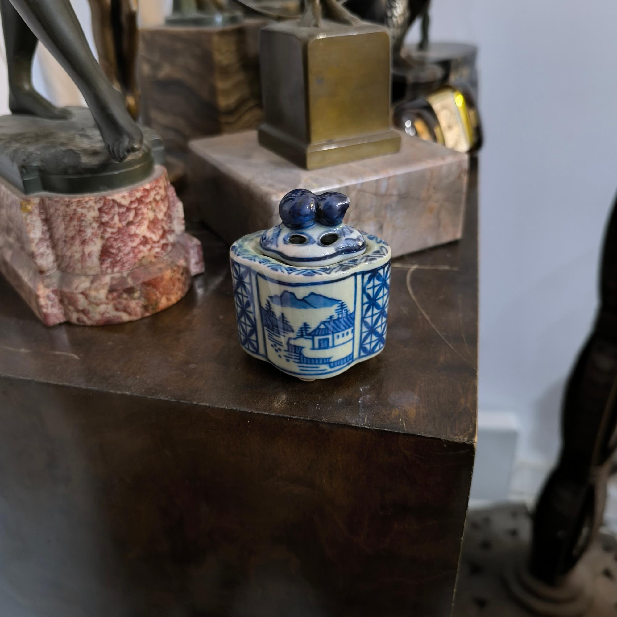 Cet exquis récipient à couvercle est un bel exemple de porcelaine bleu et blanc d'Asie orientale, qui se distingue par ses délicats motifs peints à la main et son couvercle sculptural. La Nature est ornée d'une scène paysagère réalisée en bleu