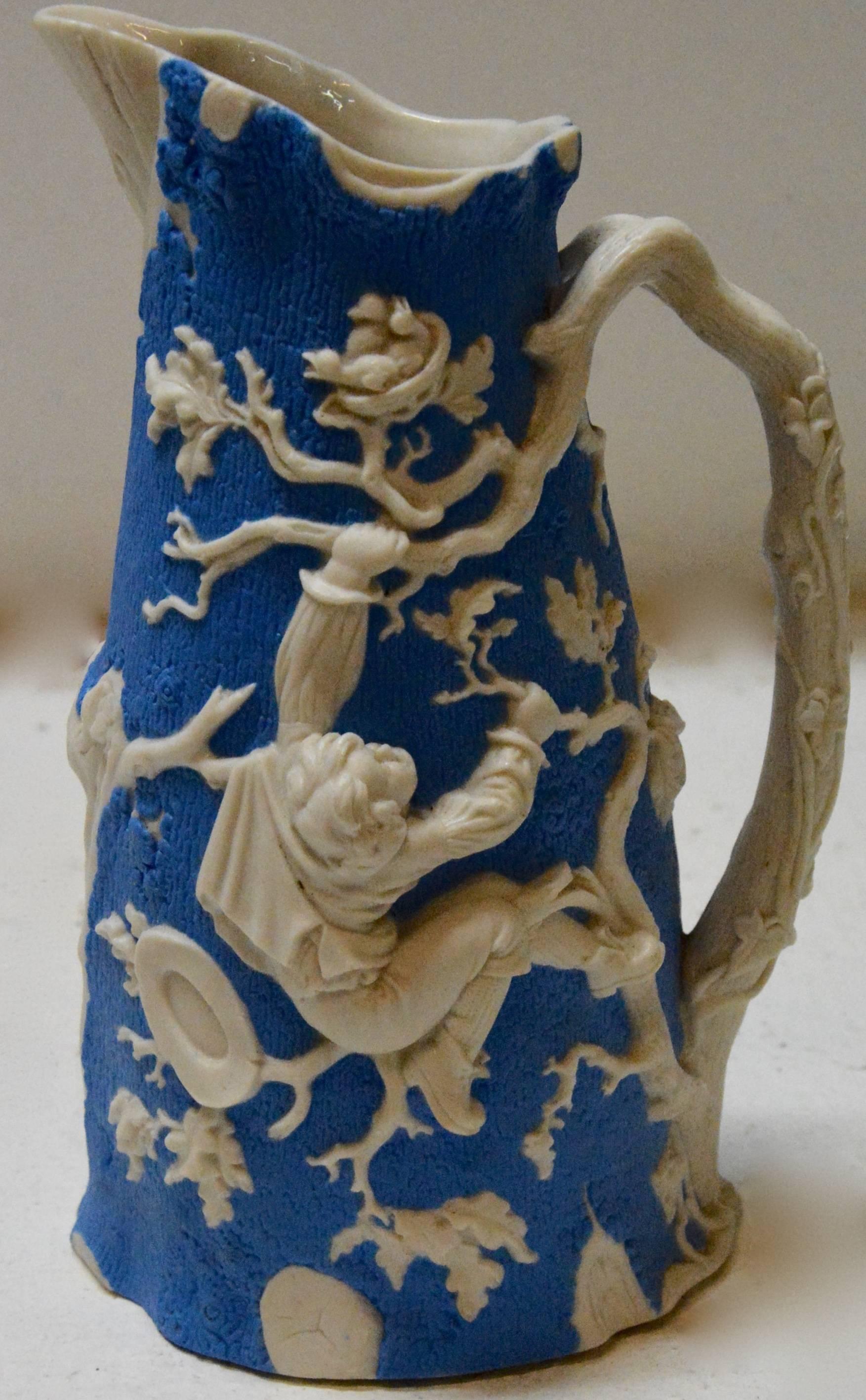 A beautiful molded earthenware pitcher made by the Jones and Walley Co. of Cobridge, Stoke-on-Trent, England. The piece features playful children play with birds. The vibrant blue and white are done in high relief with amazing details. The pitcher