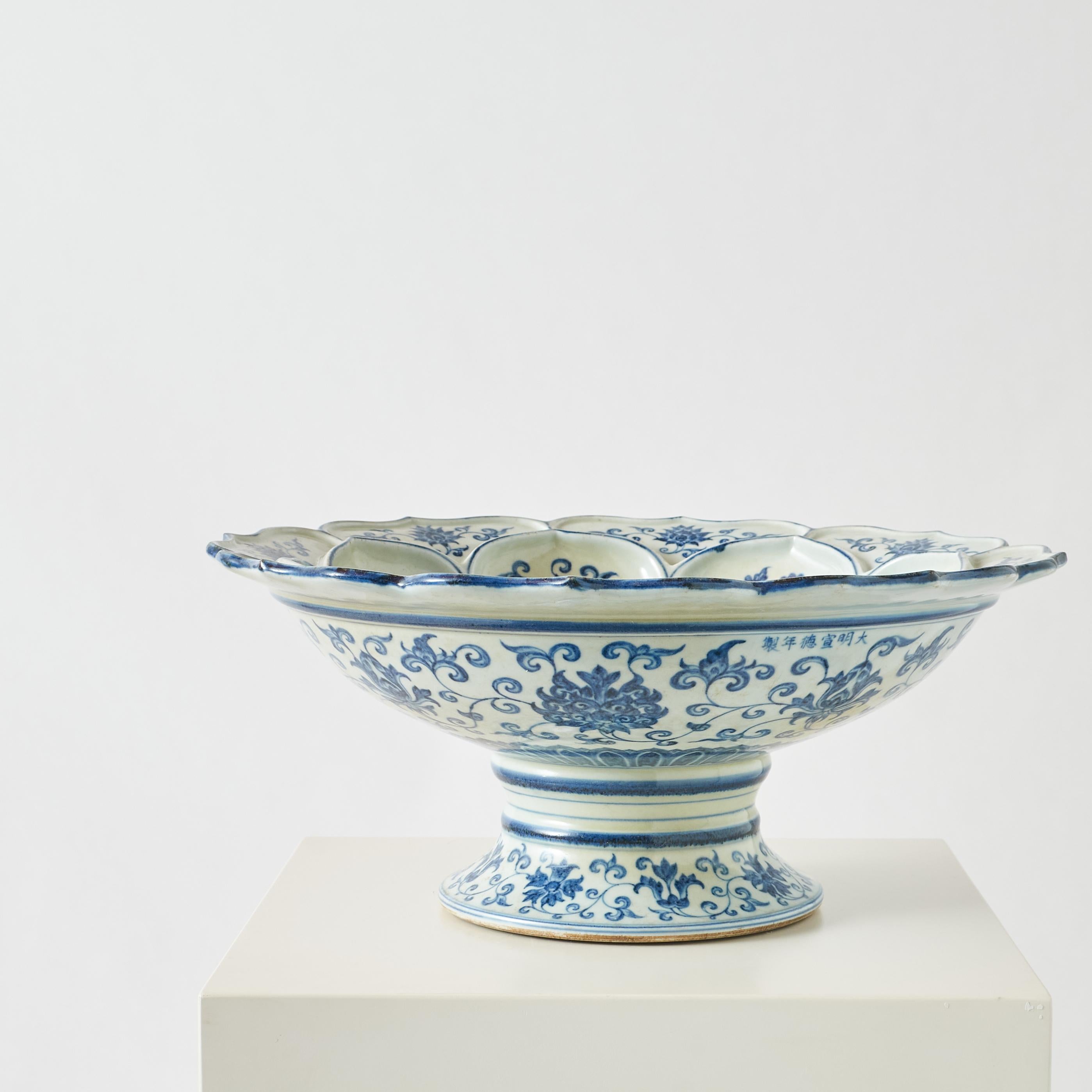 A round, high-footed plate decorated in blue and white with an interlocking lotus stem motif.