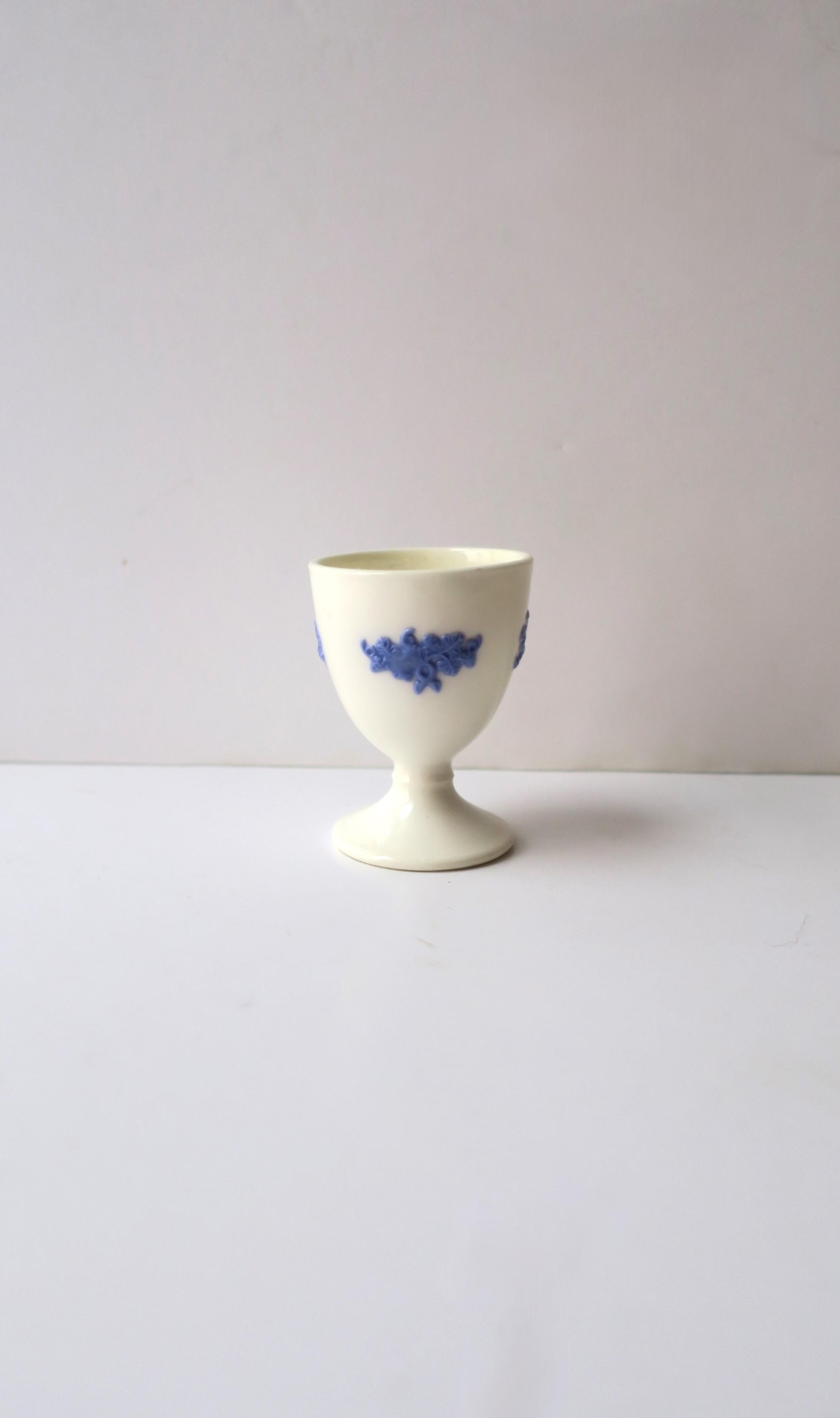 A beautiful blue and white porcelain egg holder cup, circa early-20th century. A predominantly white porcelain egg cup with applied blue porcelain detail of small leaves and vines. 

English pitcher shown available separately, search 1stDibs ref. #: