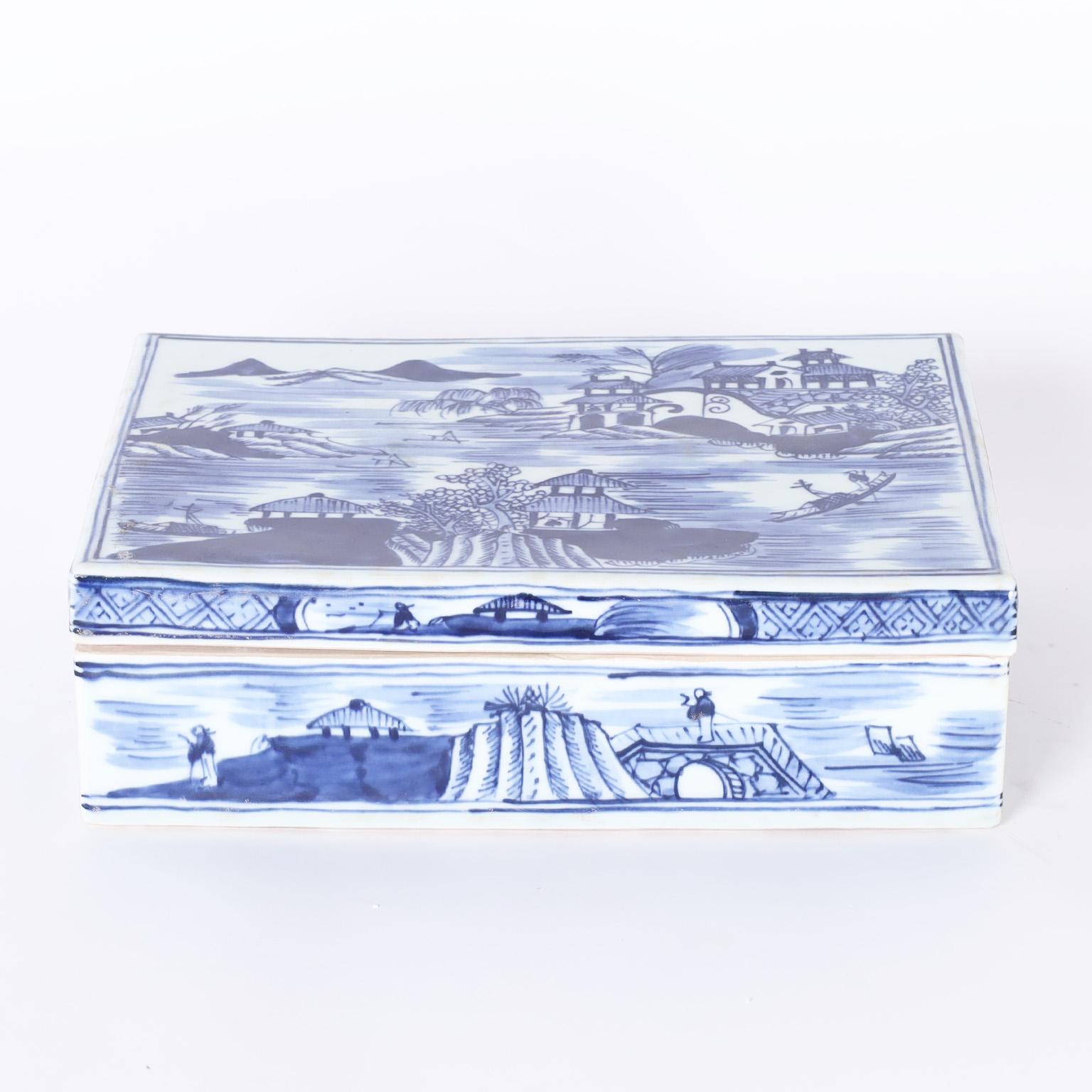 Chinese blue and white rectangular lidded box hand decorated with chinoiserie scenes with architecture, water, boats and figures.