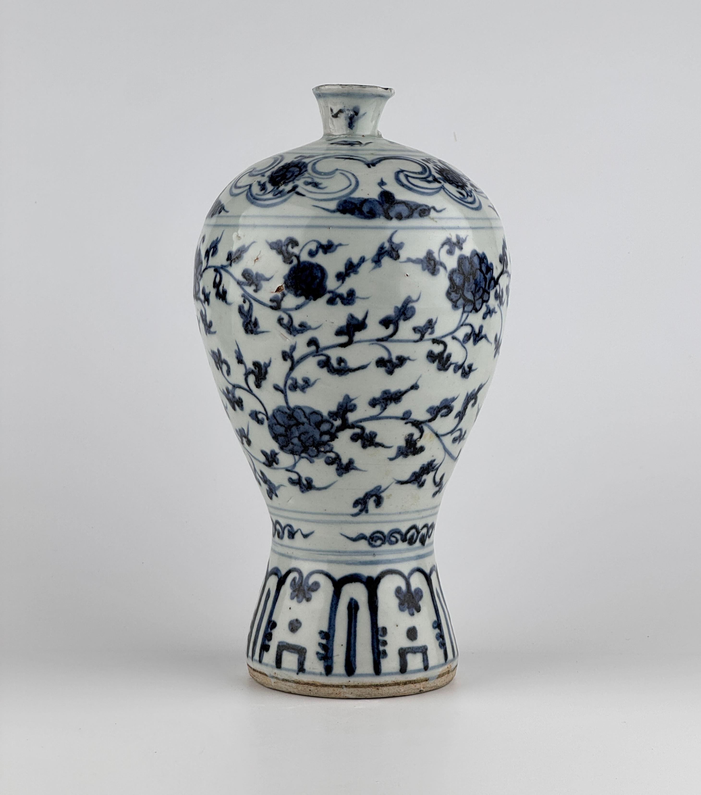 Cette pièce est présumée être un vase meiping en porcelaine bleue et blanche du milieu de la dynastie des Ming. L'ensemble du corps est décoré de rinceaux de pivoines arrangés, peints en bleu de cobalt sous glaçure. Le ton marine vif et sombre du