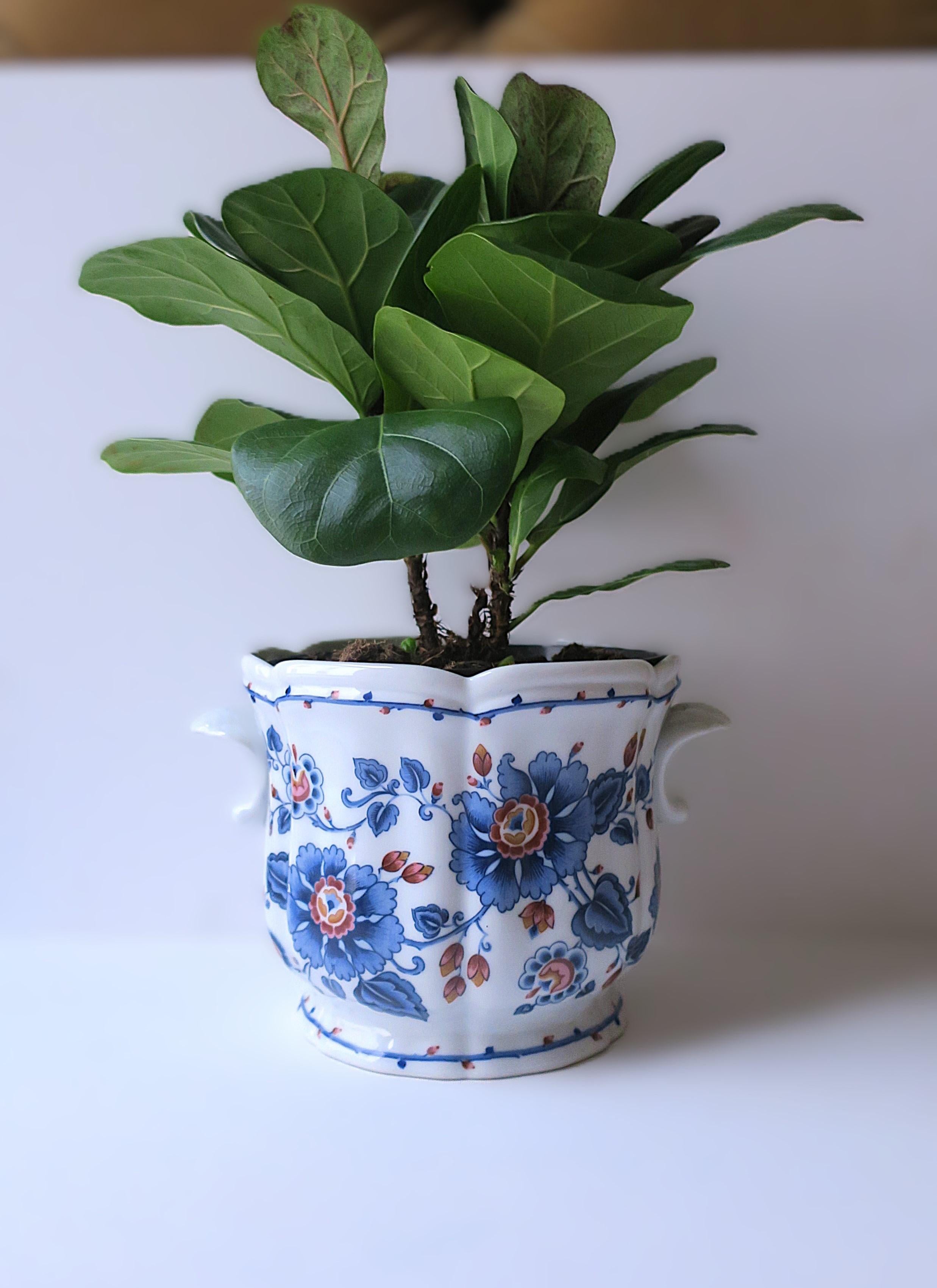 Fioriera cachepot jardinière in porcellana bianca e blu di Estee Lauder Co. Il cachepot in porcellana presenta fiori blu con tocchi di rosso bordeaux, rosa e arancione sia sul fronte che sul retro, manici a voluta su entrambi i lati e un bordo