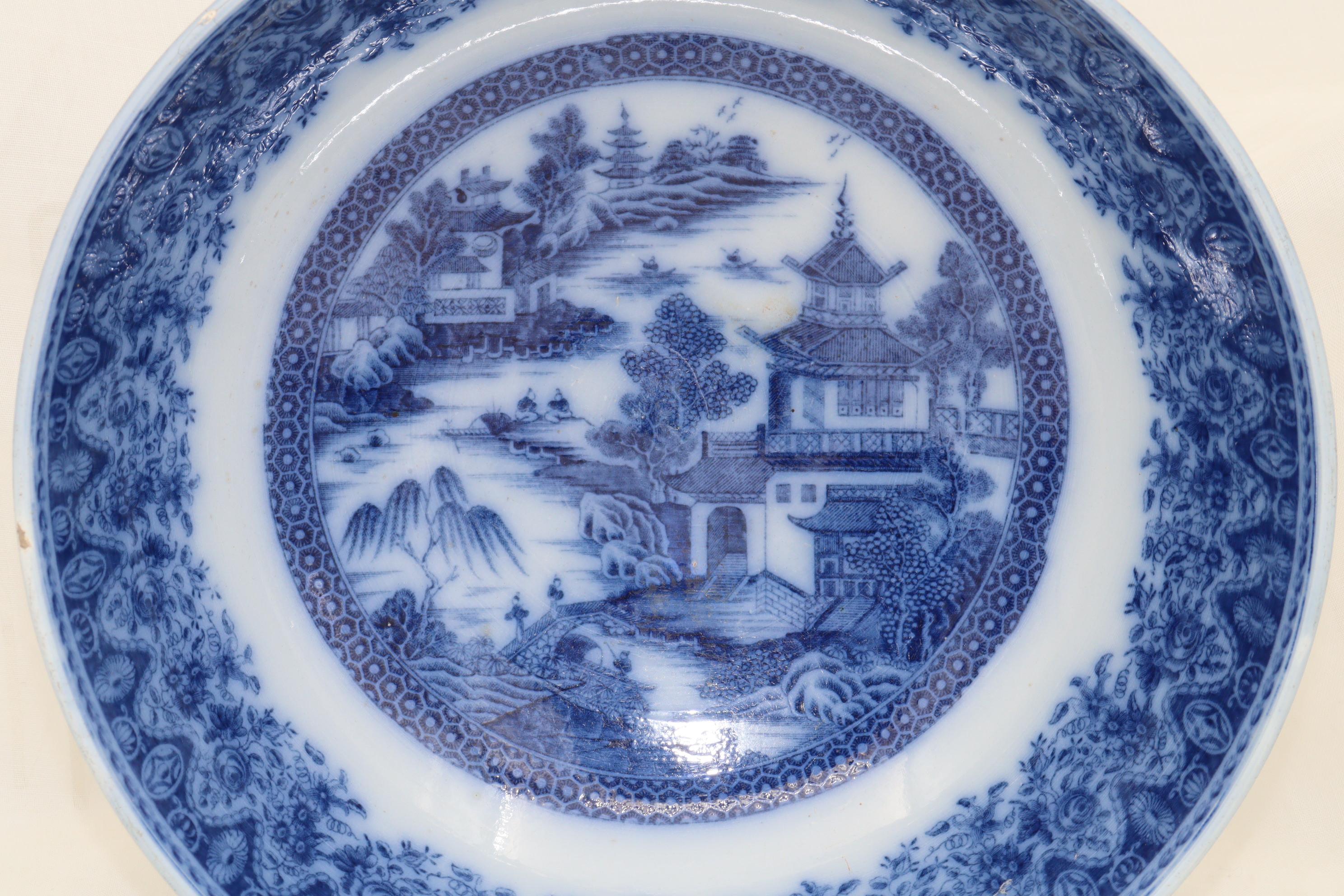 Decorated with an underglaze blue and white chinoiserie pattern, this earthenware punch bowl has been attributed to the Herculaneum factory of Liverpool. The unusual and strikingly deep border is printed inside and out and measures roughly 65 mm