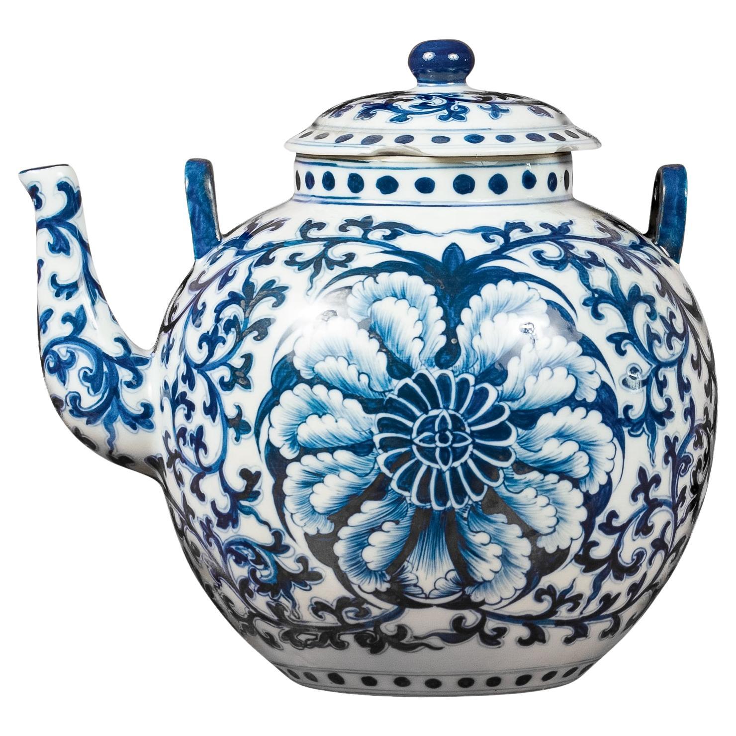 Tetera de porcelana azul y blanca con follaje en roleo y decoración floral