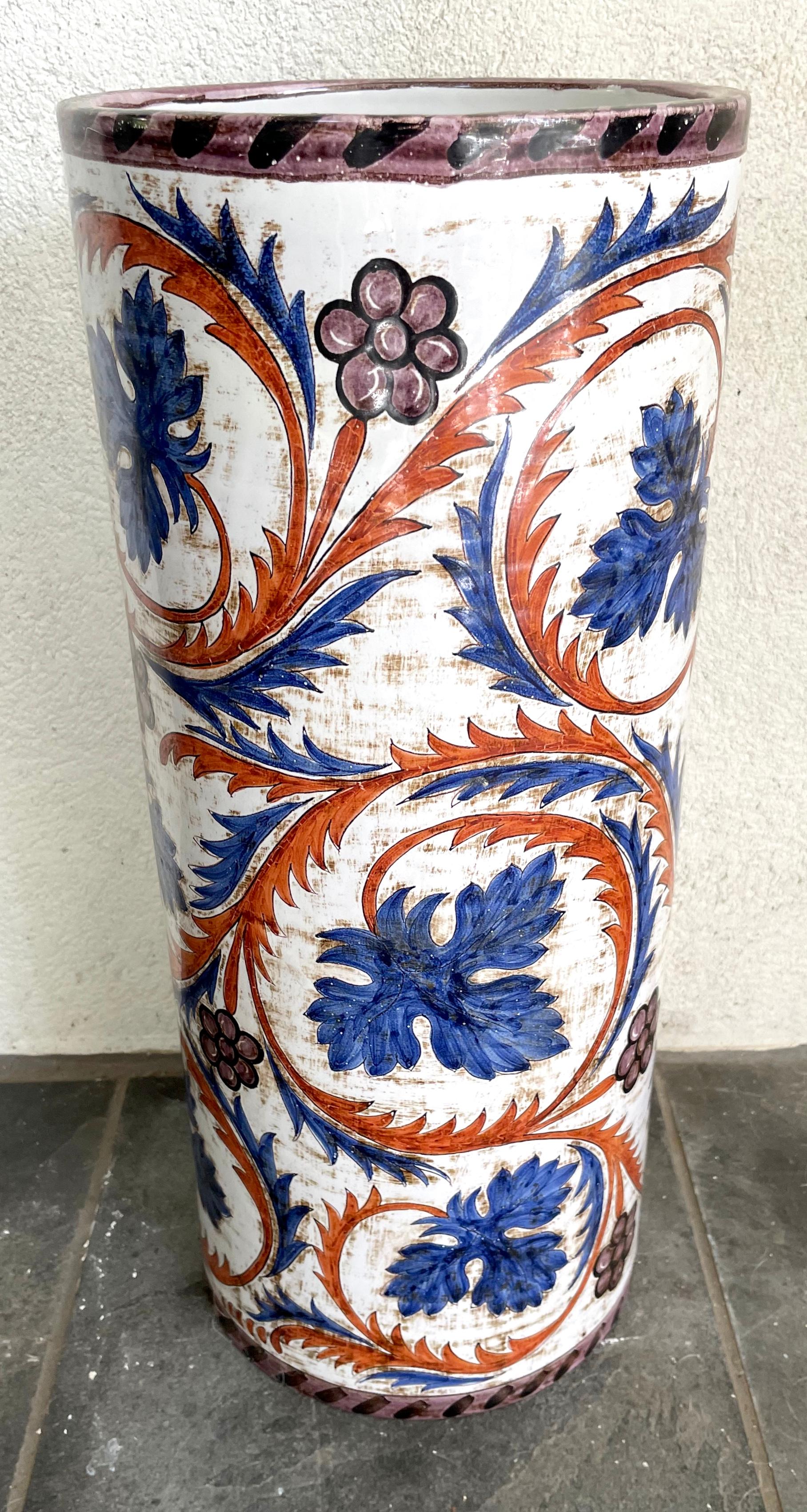 Blue and white, purple and iron red foliate umbrella stand. Antique painted Italian majolica umbrella stand with scrolling vines in blue and terracotta with eggplant flowers and rim borders all on off white background. Bottom interior long ago