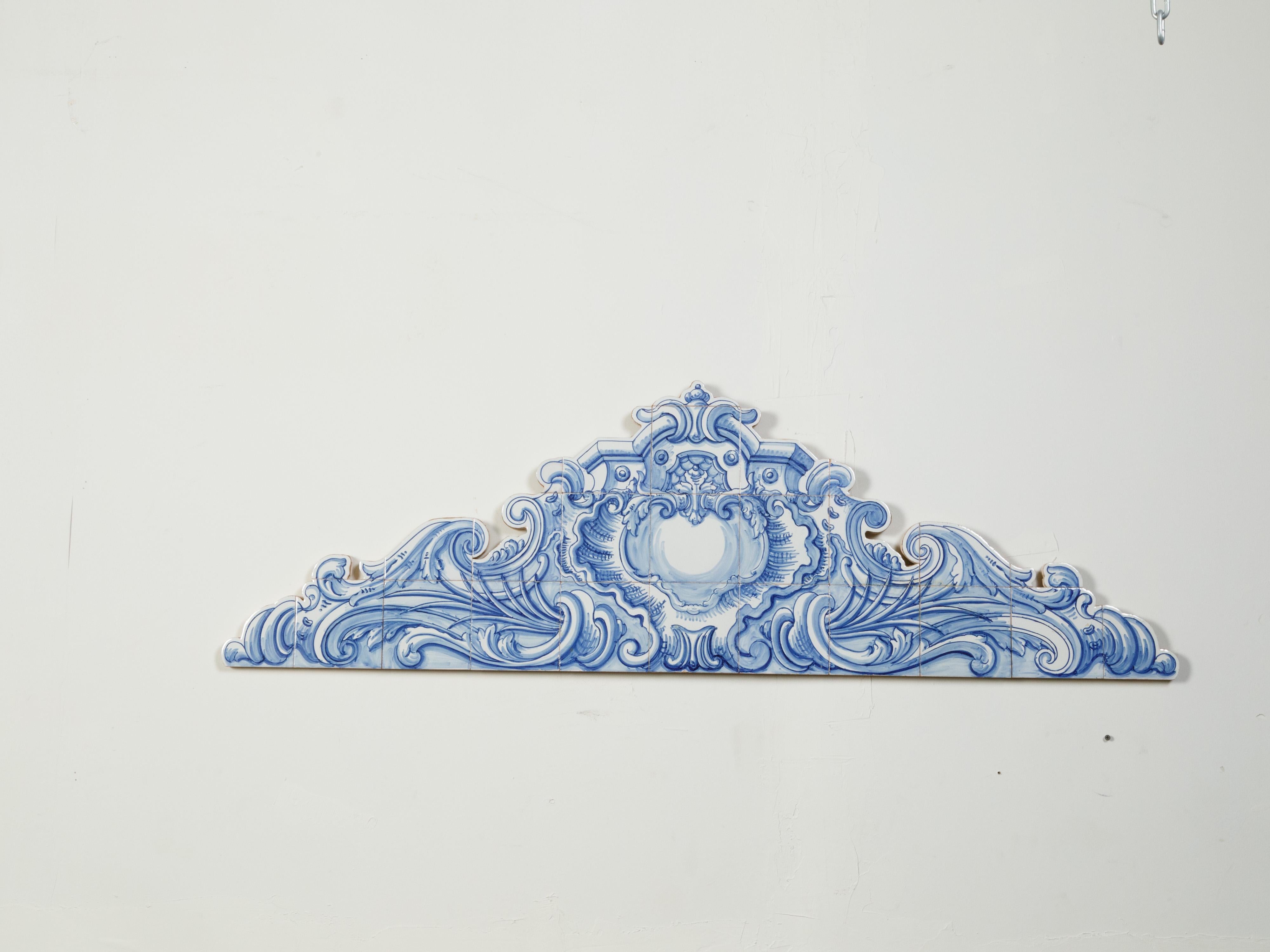 A Dutch architectural wall fragment from the 20th century, with blue and white Delft tiles mounted on wood. Created in the Netherlands, this architectural fragment features a blue and white Delft Rococo style pediment adorned with elegant scrolls