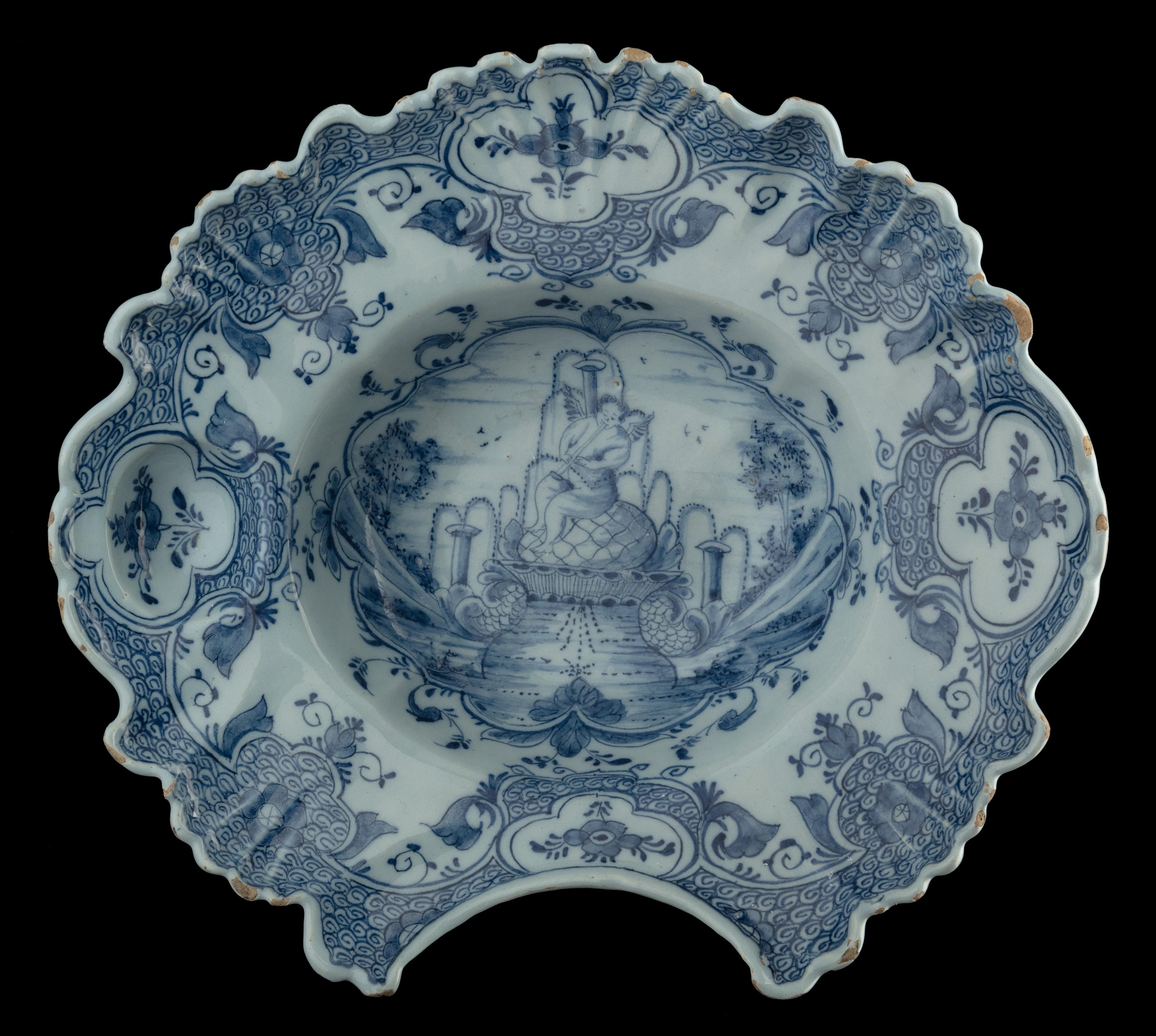 Blue and white shaving bowl with flute-playing putto on a fountain
Delft, 1759-1771 The Fortune pottery
Mark: WVDB, period of widow Elling-Van den Briel (1759-1771)

The shaving bowl is essentially oval in shape with a cantilevered, profiled rim. It