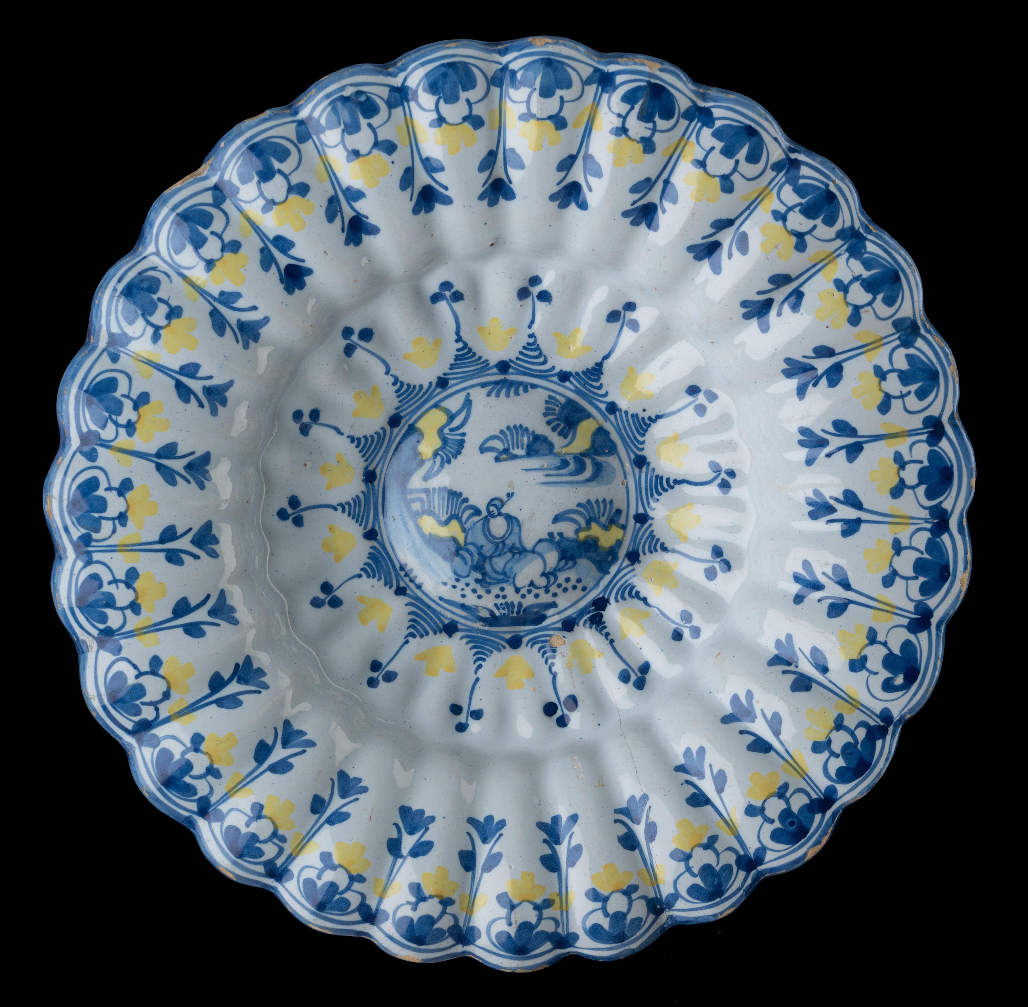 Blue and yellow chinoiserie lobed dish. Delft, 1680-1700 
Dimensions: diameter 33,2 cm / 13.07 in. 

The blue and yellow lobed dish is composed of twenty-seven double lobes around a curved centre. It is painted with a Chinese figure in an