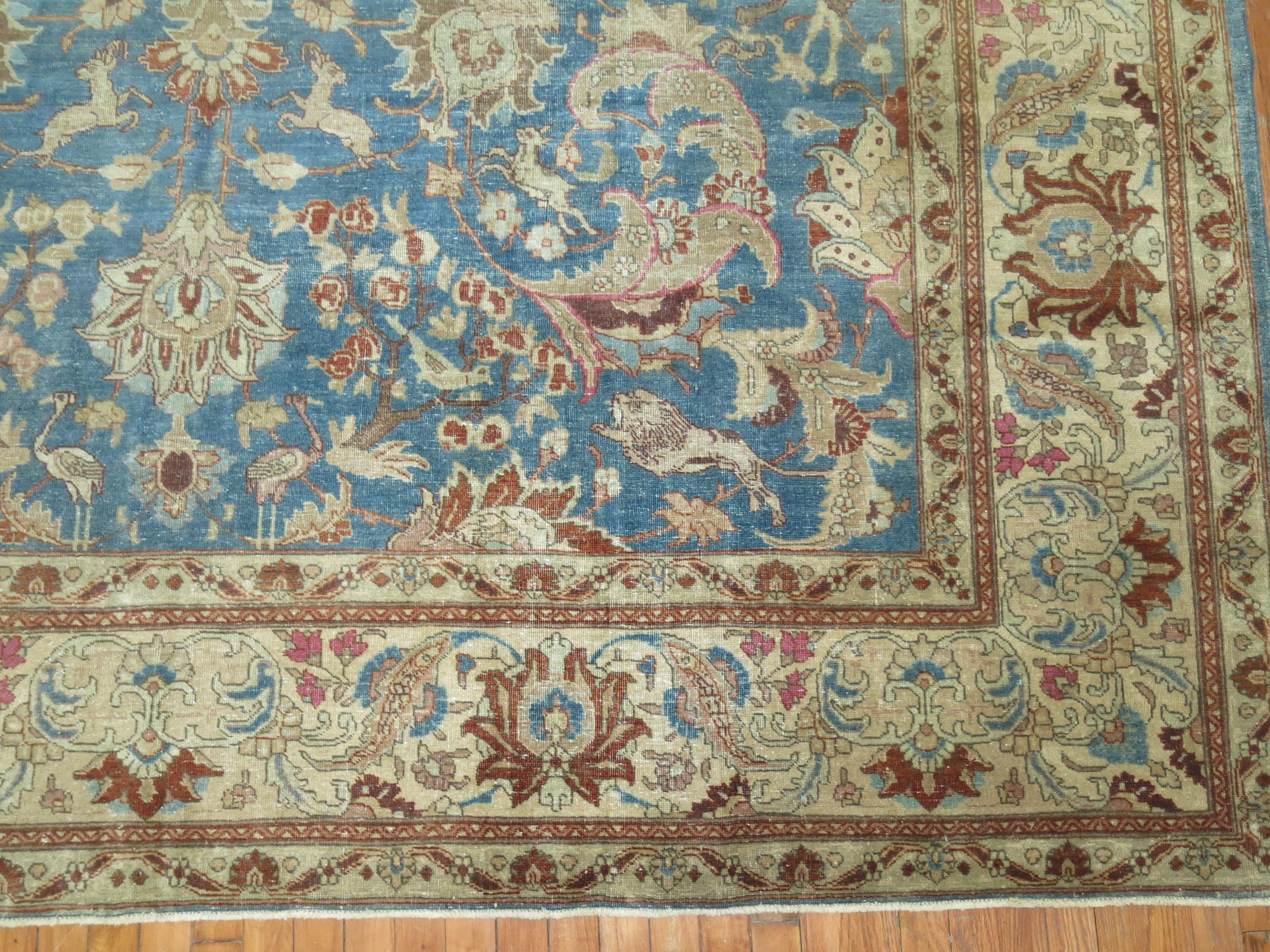 An early 20th century room size Persian Tabriz Formal rug. A sky blue field , ivory border with predominant accents in chocolate brown, pink and khaki. You can find various animals throughout the field. Lions, Pigeons, goats, reindeer's, kangaroos,