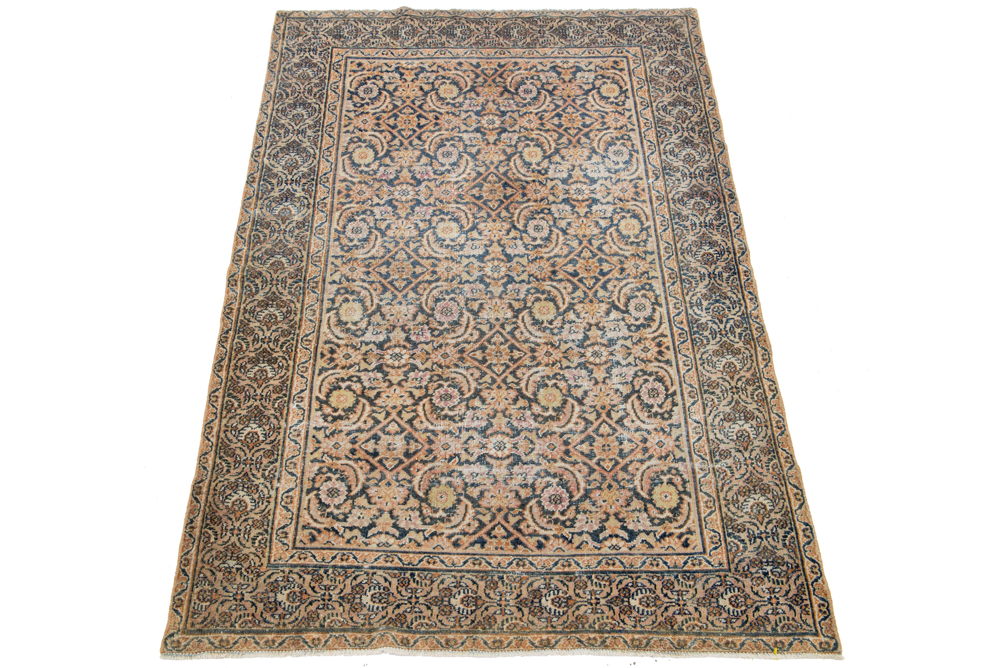 A Persian Tabriz wool rug from the 1920s showcases a handcrafted, traditional floral pattern. The design is accentuated by contrasting colors such as beige, orange, pink, and blue in the field.

This rug measures 3'9