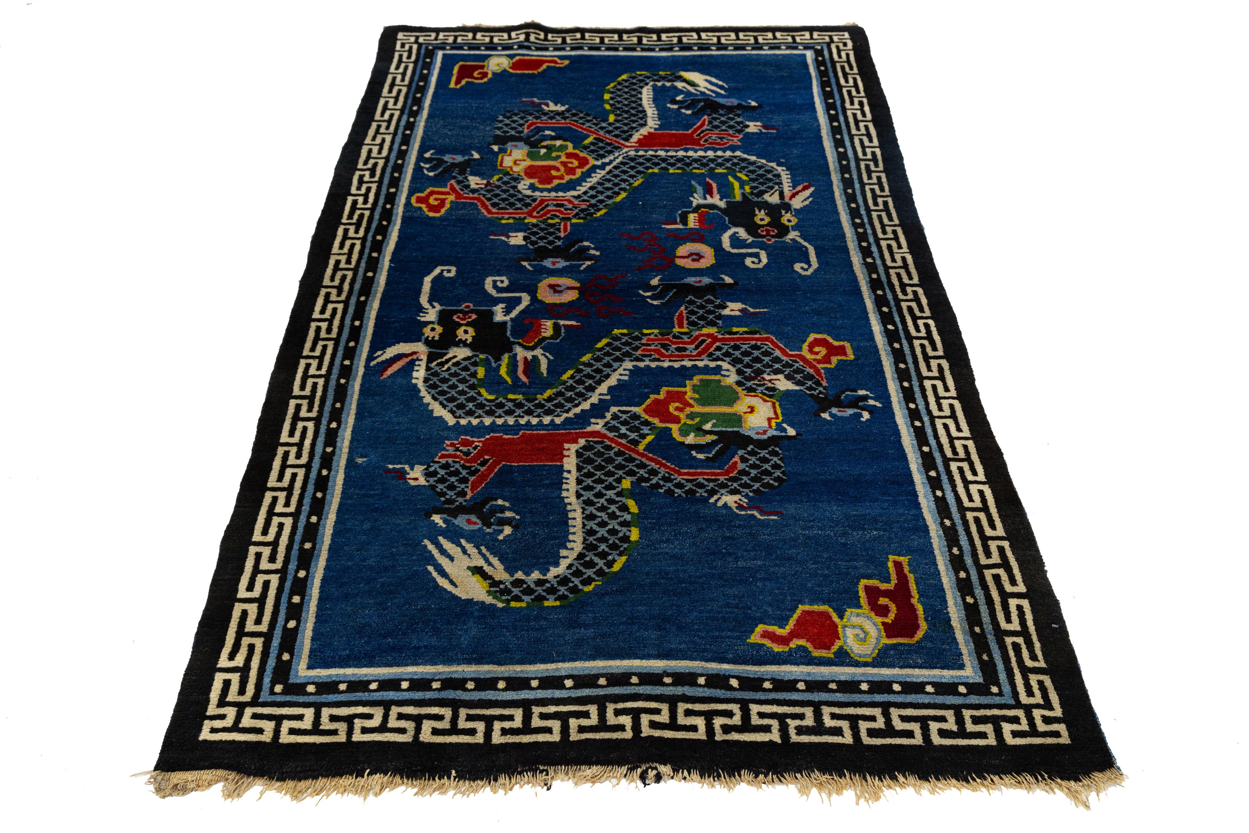 Bellissimo tappeto antico in lana annodato a mano in stile Art Deco cinese con due draghi imperiali che inseguono perle fiammeggianti, simbolo di saggezza e potere cosmico. Tessuti a mano su un ricco campo blu cobalto, i draghi serpentini sono resi