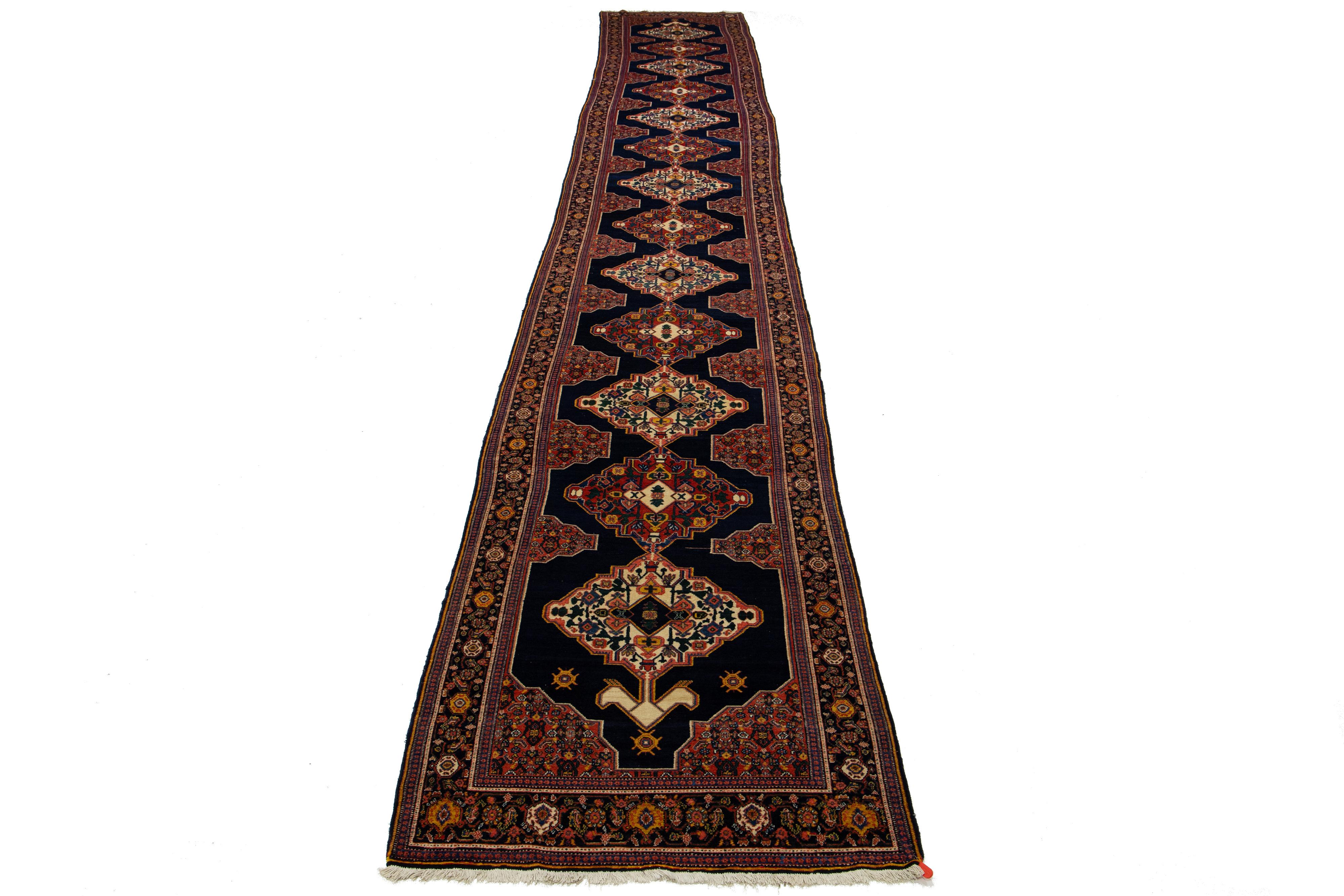 Ce tapis persan Malayer du XXe siècle, fait à la main, présente un champ bleu marine avec des accents rouges, jaunes et verts tout au long du motif.

Ce tapis mesure 3'7
